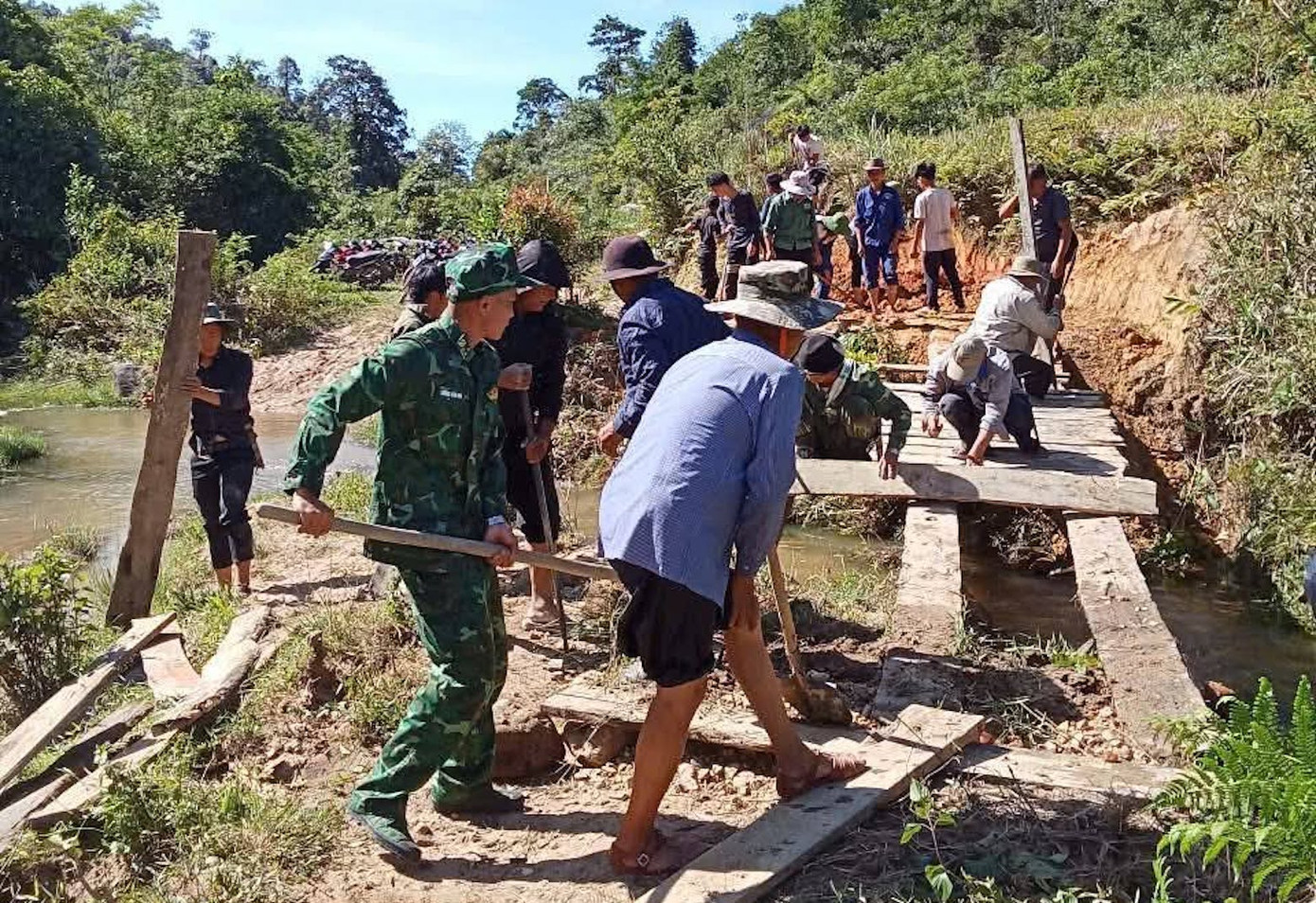 Hàng chục người gồm các cán bộ chiến sĩ Đồn Biên phòng Tri Lễ và người dân đã sửa lại cây cầu, đảm bảo an toàn cho người dân đi lại.