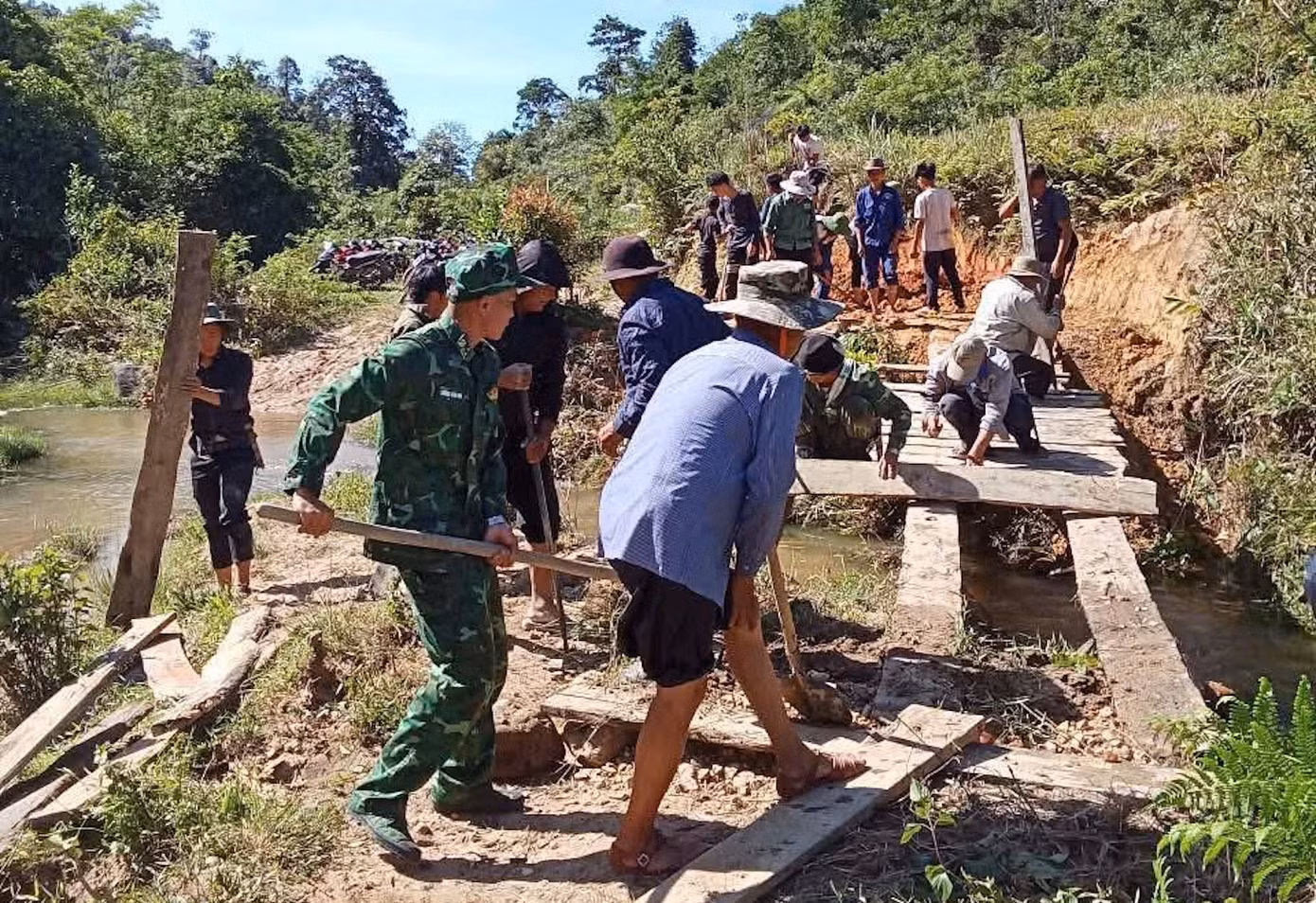 Hàng chục người gồm các cán bộ chiến sĩ Đồn Biên phòng Tri Lễ và người dân đã sửa lại cây cầu, đảm bảo an toàn cho người dân đi lại.