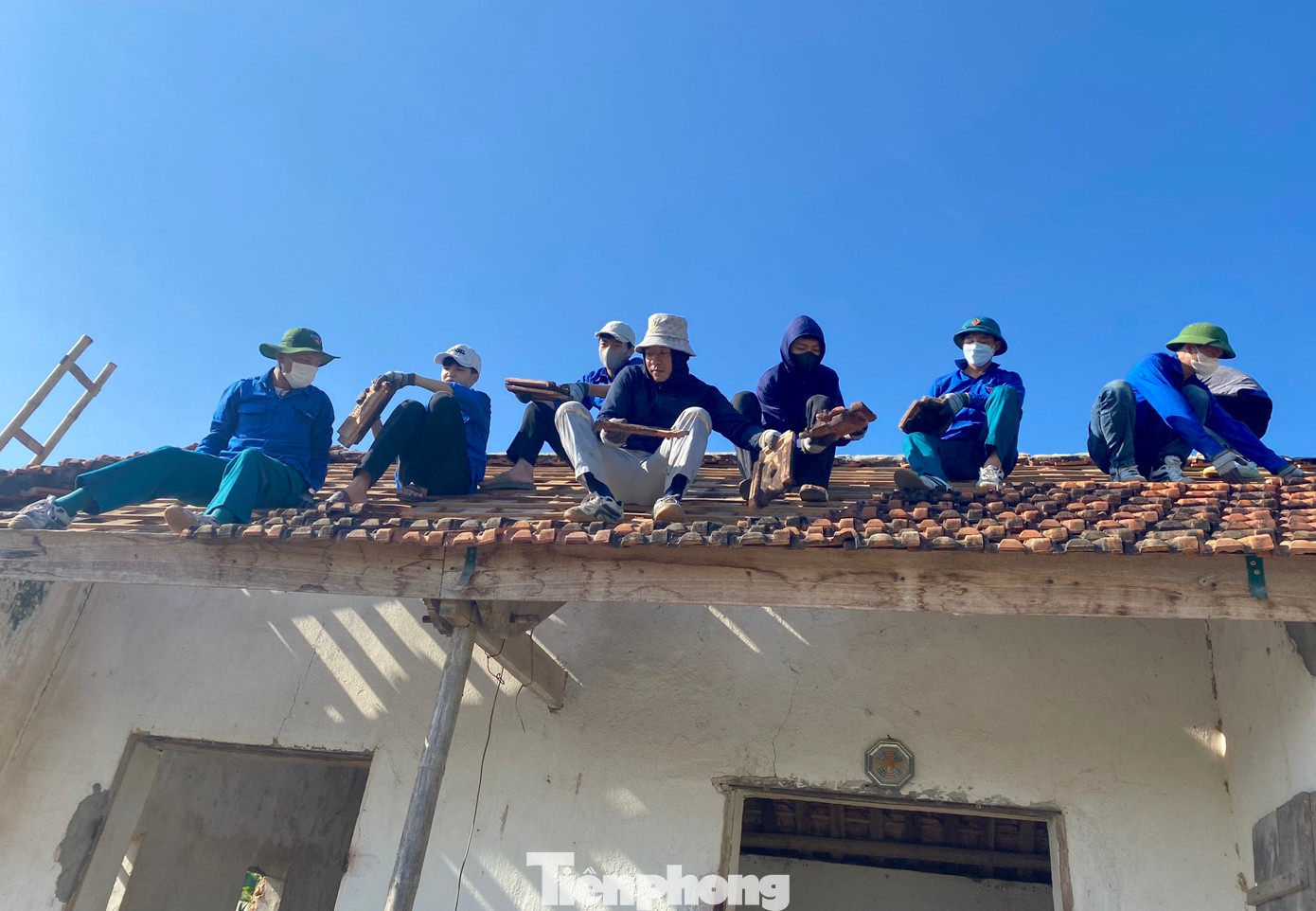 Bất kể ở dưới đất hay trên mái nhà cũng đều có màu áo xanh tình nguyện hỗ trợ.