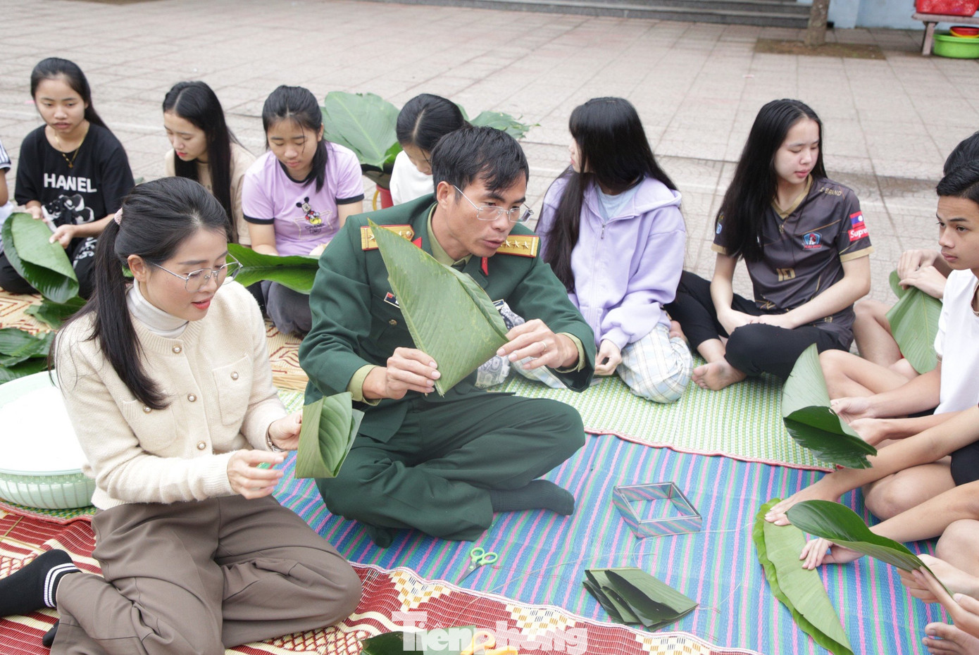 Các cán bộ chiến sĩ hướng dẫn từ việc chọn lá, cắt lá, chuẩn bị nguyên vật liệu đến việc gấp lá và gói bánh.