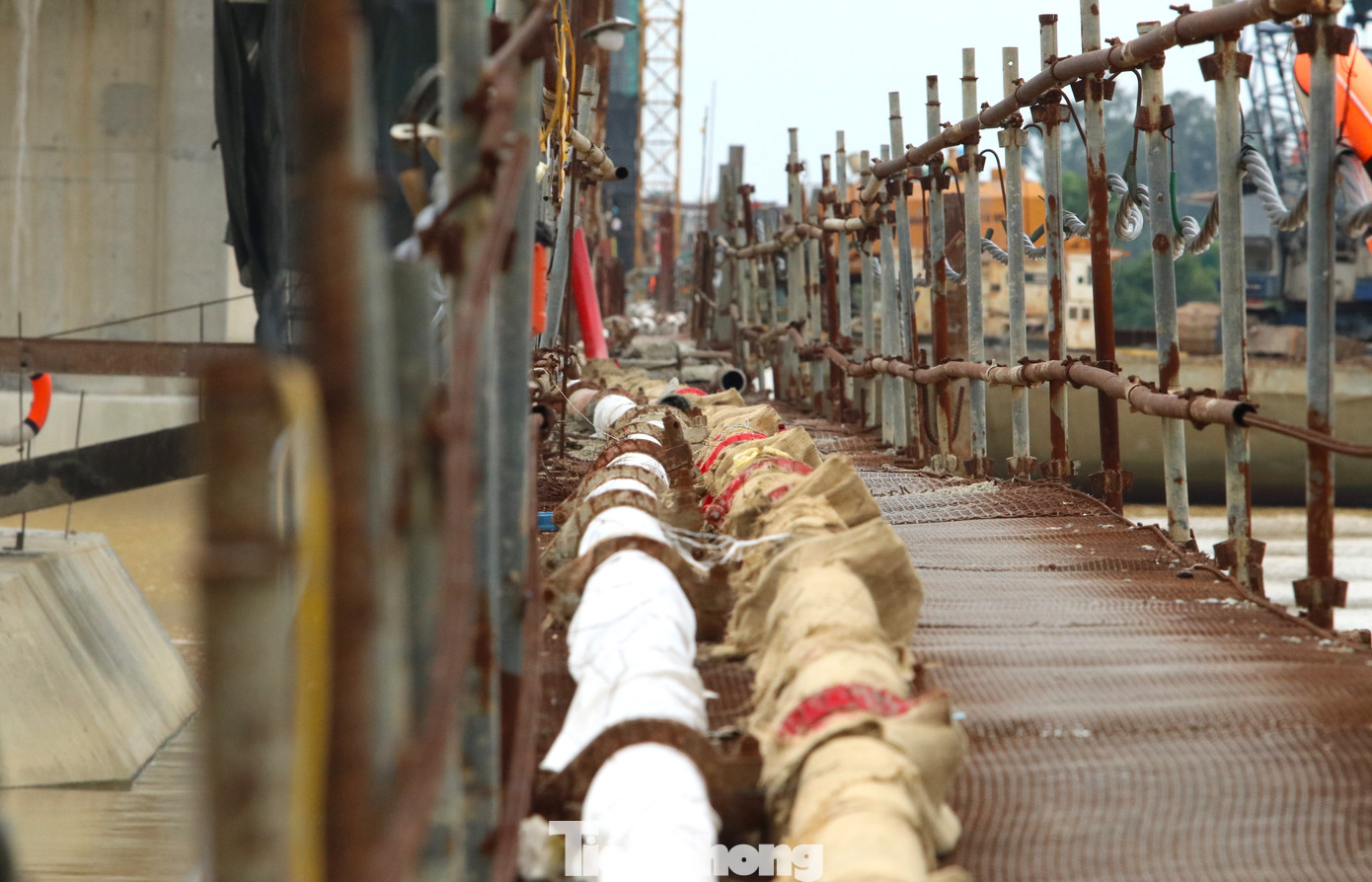 Do cây cầu vượt sông nên các đơn vị thi công làm một đường công vụ bằng sắt dẫn ra các mố trụ cầu. Trên đường dẫn có nhiều ống được lắp đặt để dẫn đường điện và nhiên liệu phục vụ thi công cầu. Do cây cầu vượt sông nên các đơn vị thi công làm một đường công vụ bằng sắt dẫn ra các mố trụ cầu. Trên đường dẫn có nhiều ống được lắp đặt để dẫn đường điện và nhiên liệu phục vụ thi công cầu.