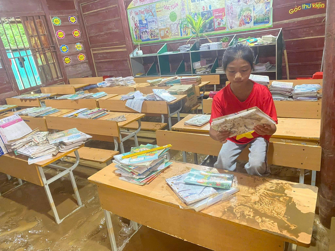 Nền phòng học bị bao phủ bởi một lớp bùn dày. Sách vở của các em bị nhấn chìm trong nước lũ.