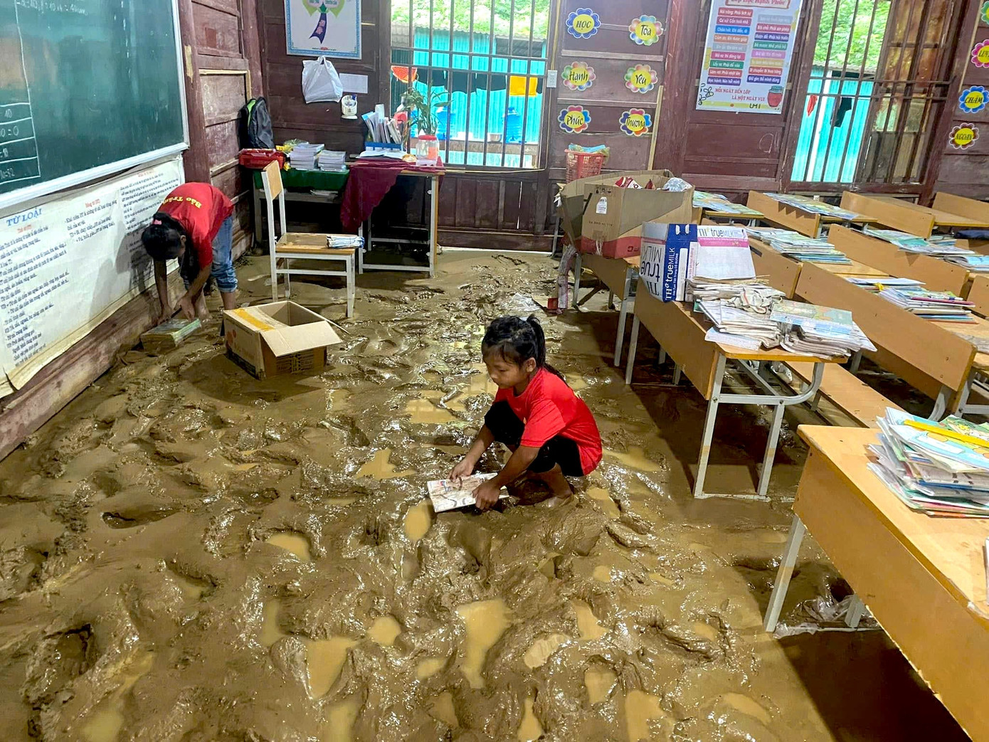 Nền phòng học bị bao phủ bởi một lớp bùn dày. Sách vở của các em bị nhấn chìm trong nước lũ.
