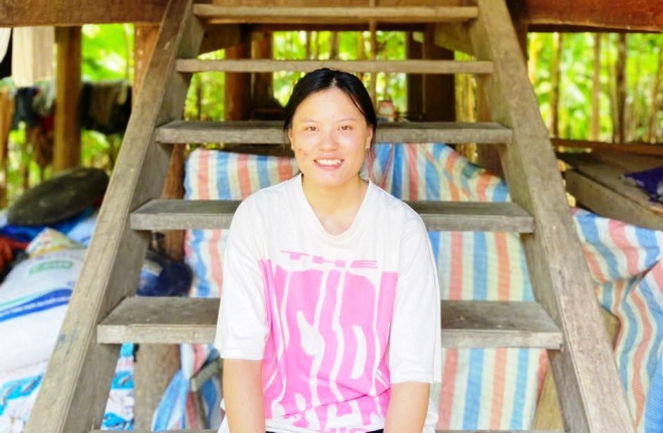 Em Vi Thị Thảo bên căn nhà sàn của gia đình.