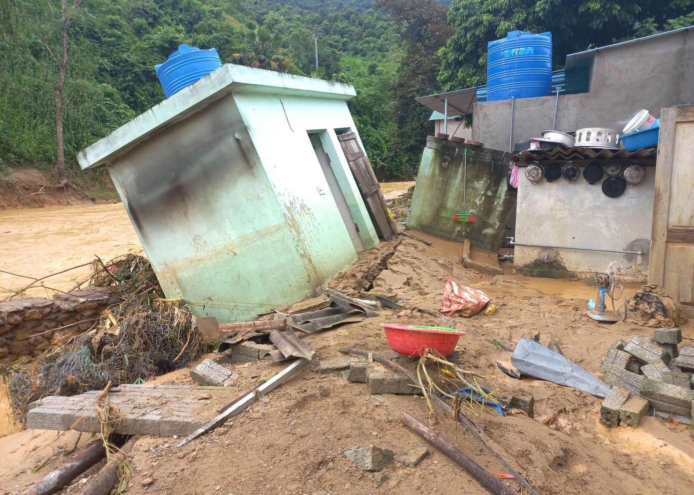 Một công trình phụ bị nước lũ làm sạt lở, đổ nghiêng về phía suối.