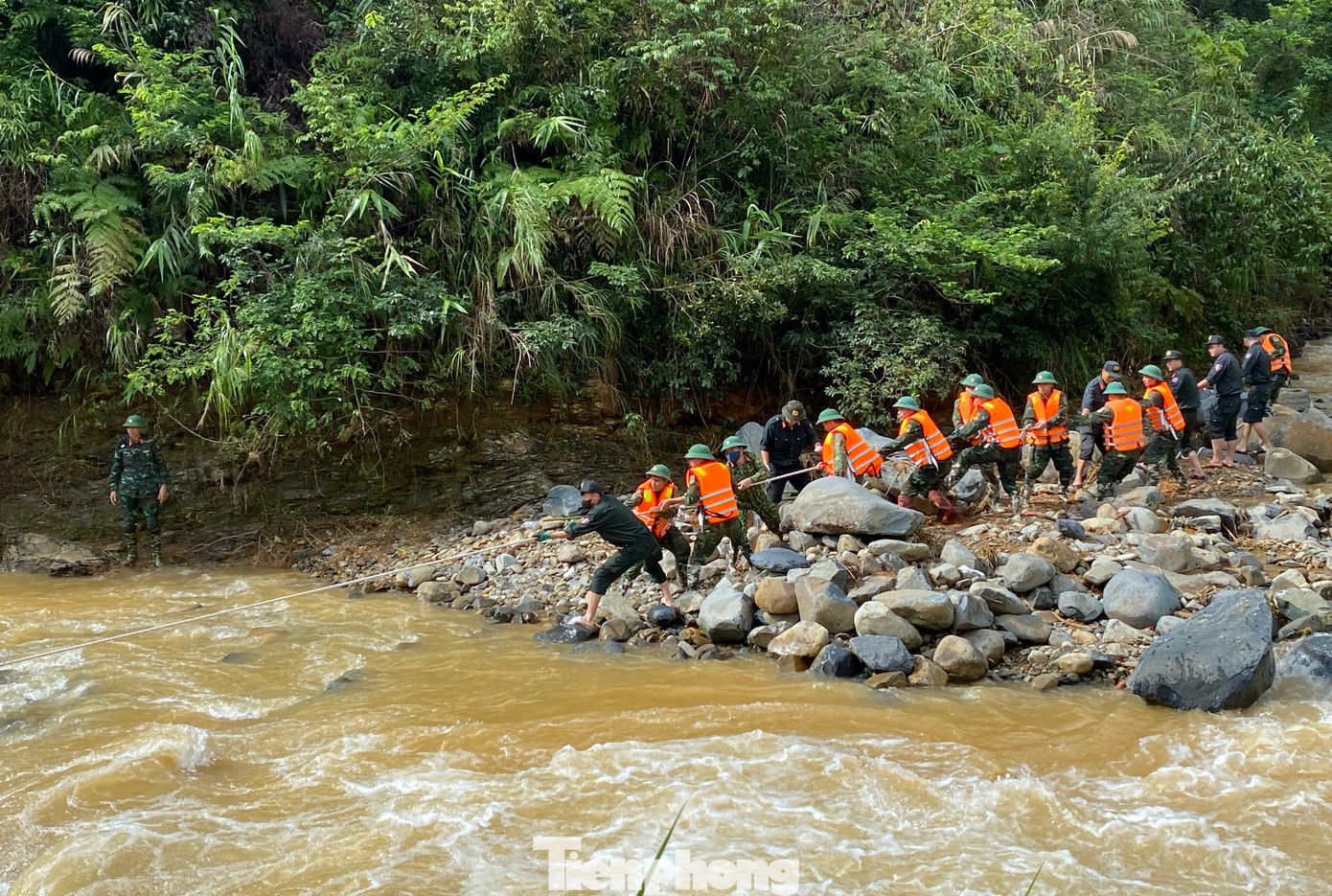 Các cán bộ chiến sĩ Lữ đoàn Công binh 575 kết hợp với lực lượng chức năng dùng dây thừng kéo những chiếc xe máy mắc kẹt dưới suối lên bờ.
