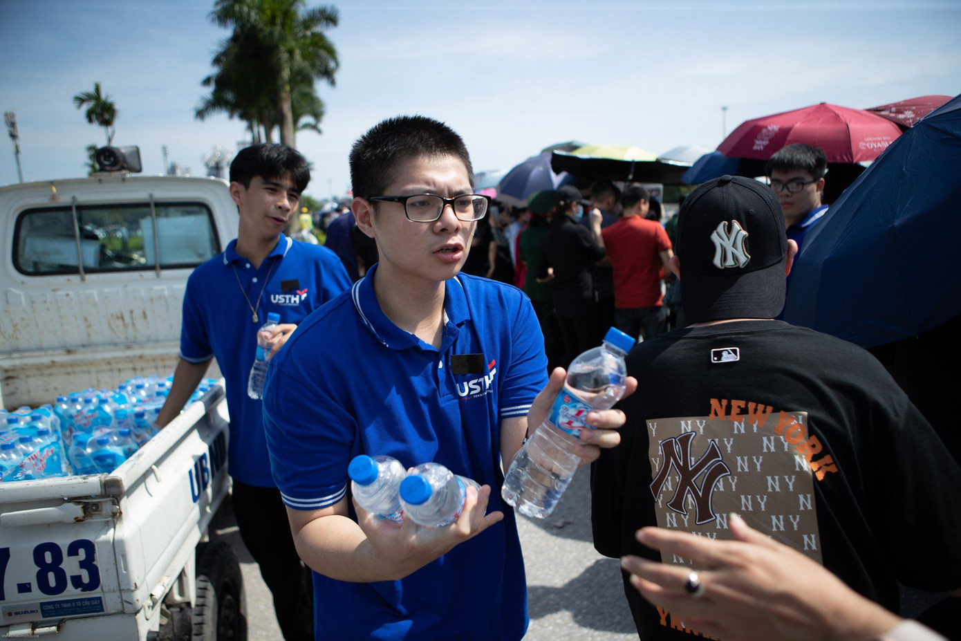 Sinh viên USTH tham gia hỗ trợ nước miễn phí đến người dân chờ đoàn xe chở linh cữu Tổng Bí thư đi qua.