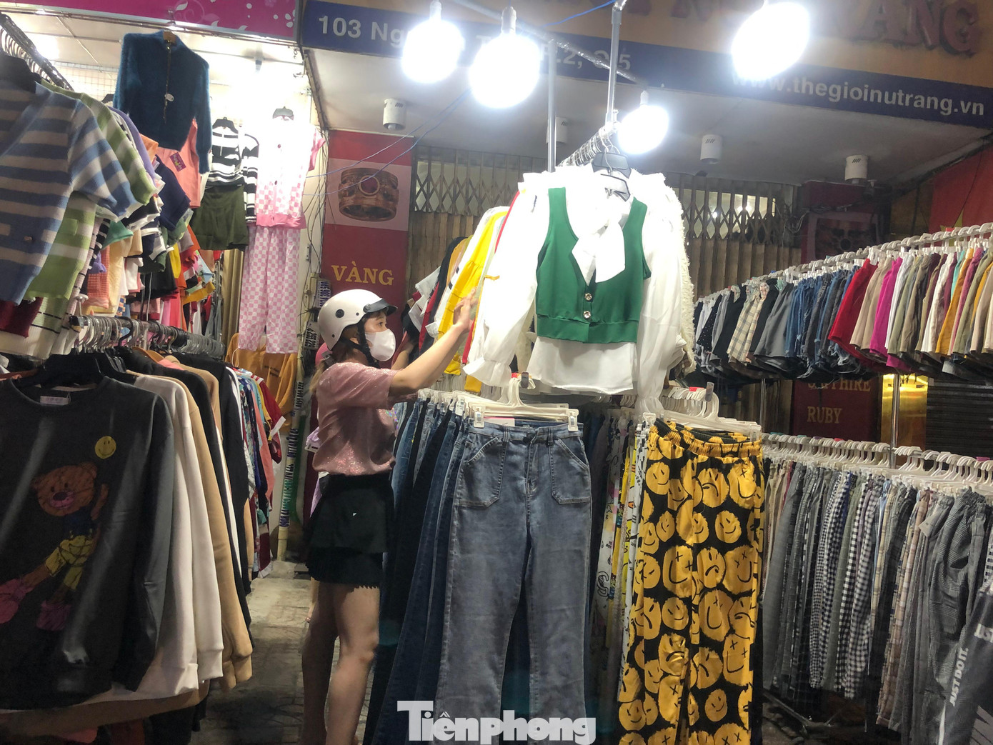 Một nữ khách hàng trẻ tuổi chọn quần áo phù hợp với mình để đi chơi Tết.