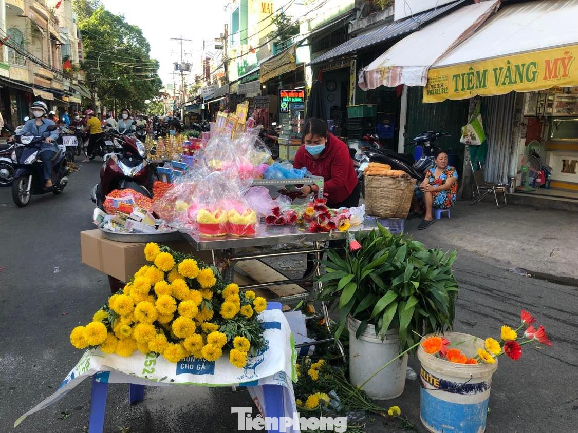 Tiểu thương bày bán thêm bông vạn thọ với giá 20.000-25.000 đồng/cây, bánh bông lan, đồ cúng... chờ khách mua.