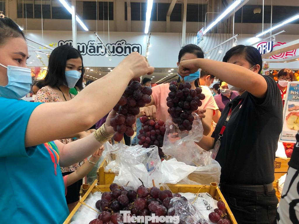 Nho đỏ Peru khuyến mãi sốc với 99.000 đồng/kg, rẻ gần 50% so với ngày thường được nhiều khách hàng chọn mua. &quot;Hôm nay giá rẻ bất ngờ, trước đó tôi còn mua với giá 177.000 đồng/kg&quot; - chị Hà (35 tuổi) phấn khởi mua được hàng ngon giá rẻ.