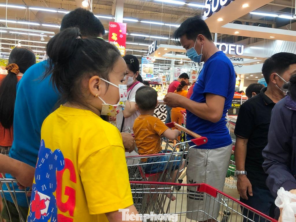 Do quá đông người, nhiều trẻ tỏ ra khó chịu, mệt mỏi khi phải đeo khẩu trang chờ đợi cha mẹ mua sắm Tết.
