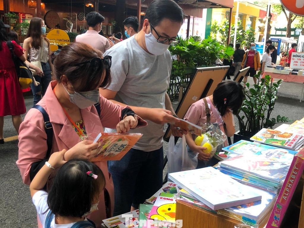 Một gia đình trẻ đưa con đi chơi, chọn mua sách. Một gia đình trẻ đưa con đi chơi, chọn mua sách.