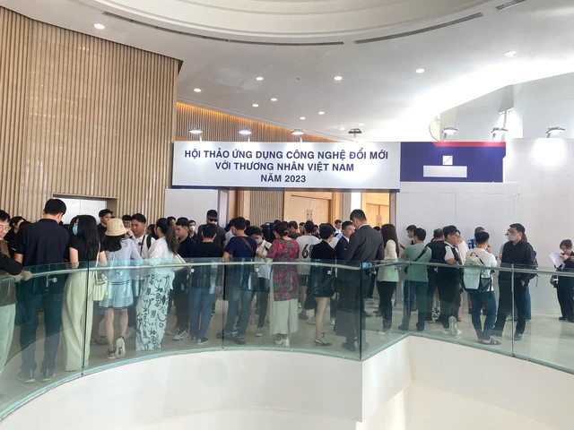 Hàng trăm người tham gia đang đứng đợi. Bảng tên hội thảo được che phần logo và tên đơn vị tổ chức; Ảnh: Lê Tỉnh