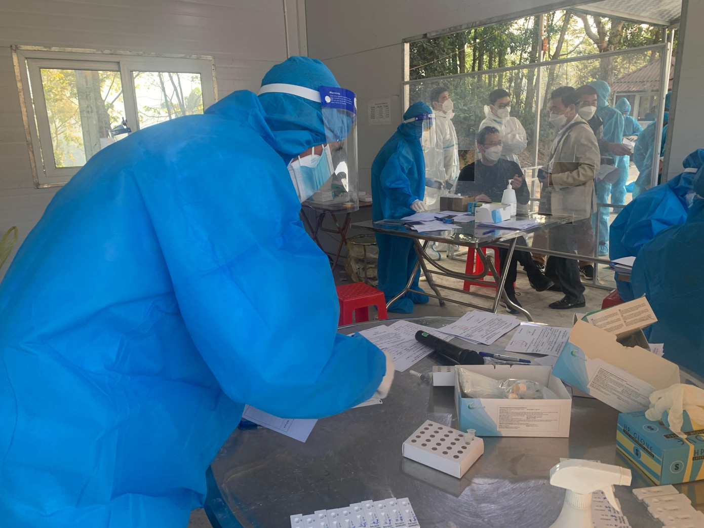 Tại "vùng đệm" khu trung chuyển Bản Liếp, các nhân viên y tế thực hiện các công việc phòng chống dịch COVID-19 một cách nghiêm túc -Ảnh: Duy Chiến