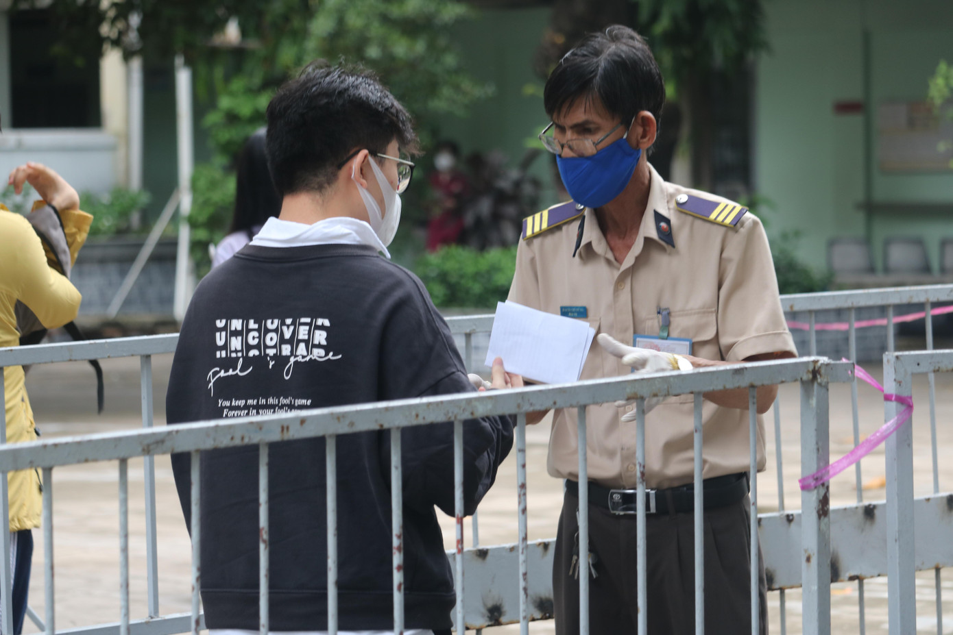Thí sinh xuất trình tại cổng phiếu báo danh và giấy xét nghiệm COVID-19 của ngày 3/7 - điều kiện bắt buộc để có thể bước vào phòng thi - Ảnh: Viên Vy