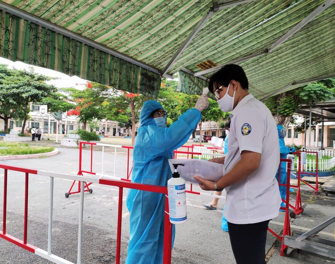 Thí sinh được đo thân nhiệt trước buổi thi tại điểm thi THCS Lê Quý Đôn (TP. Thủ Đức, TPHCM) sáng 7/7. Những người thực hiện đo thân nhiệt cho thí sinh mặc đồ bảo hộ cẩn thận.