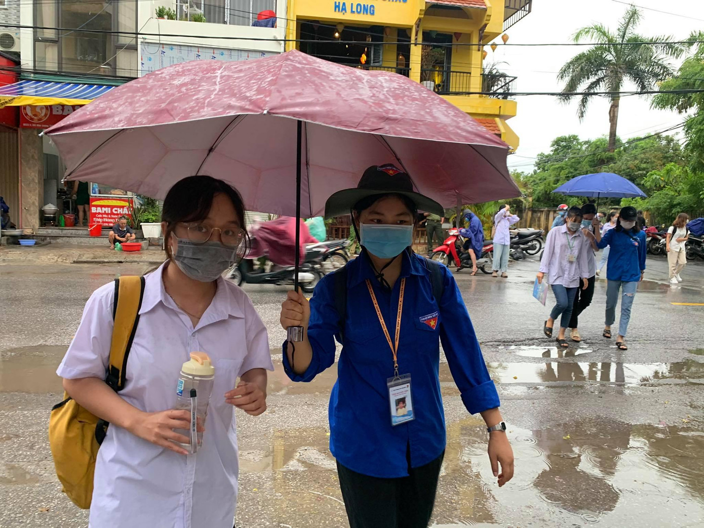 Tình nguyện viên che mưa giúp thí sinh vào phòng thi. Ảnh chụp sáng 8/7 tại trường THPT Hoài Đức A, Hà Nội