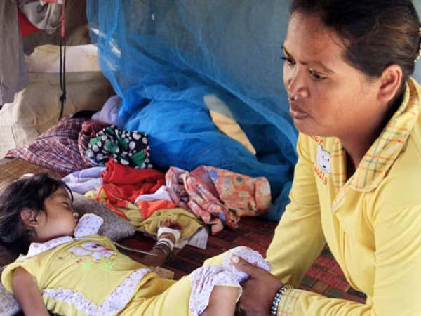 Mean Thida, bốn tuổi, mắc bệnh lạ đang nằm bên mẹ và được truyền huyết thanh tại nhà, gần một bãi rác ở làng Sambour, ngoại ô thủ đô Phnom Penh, Campuchia, hôm 9-7 Ảnh: AP