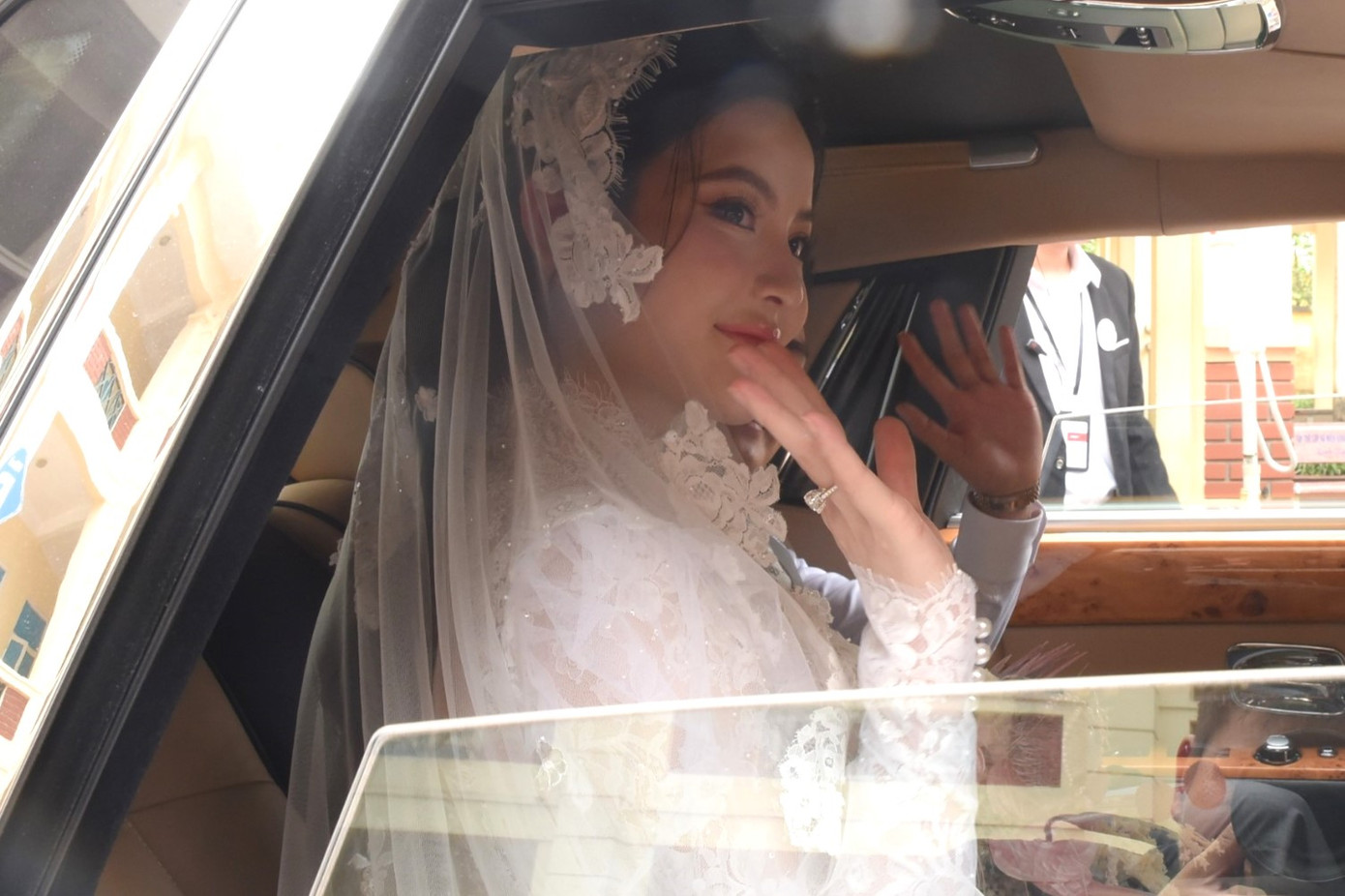 Cô dâu vẫy tay chào người thân, ống kính phóng viên và người dân hiếu kỳ trên xế hộp Rolls-Royce Phantom có giá lên đến 16 tỷ đồng.