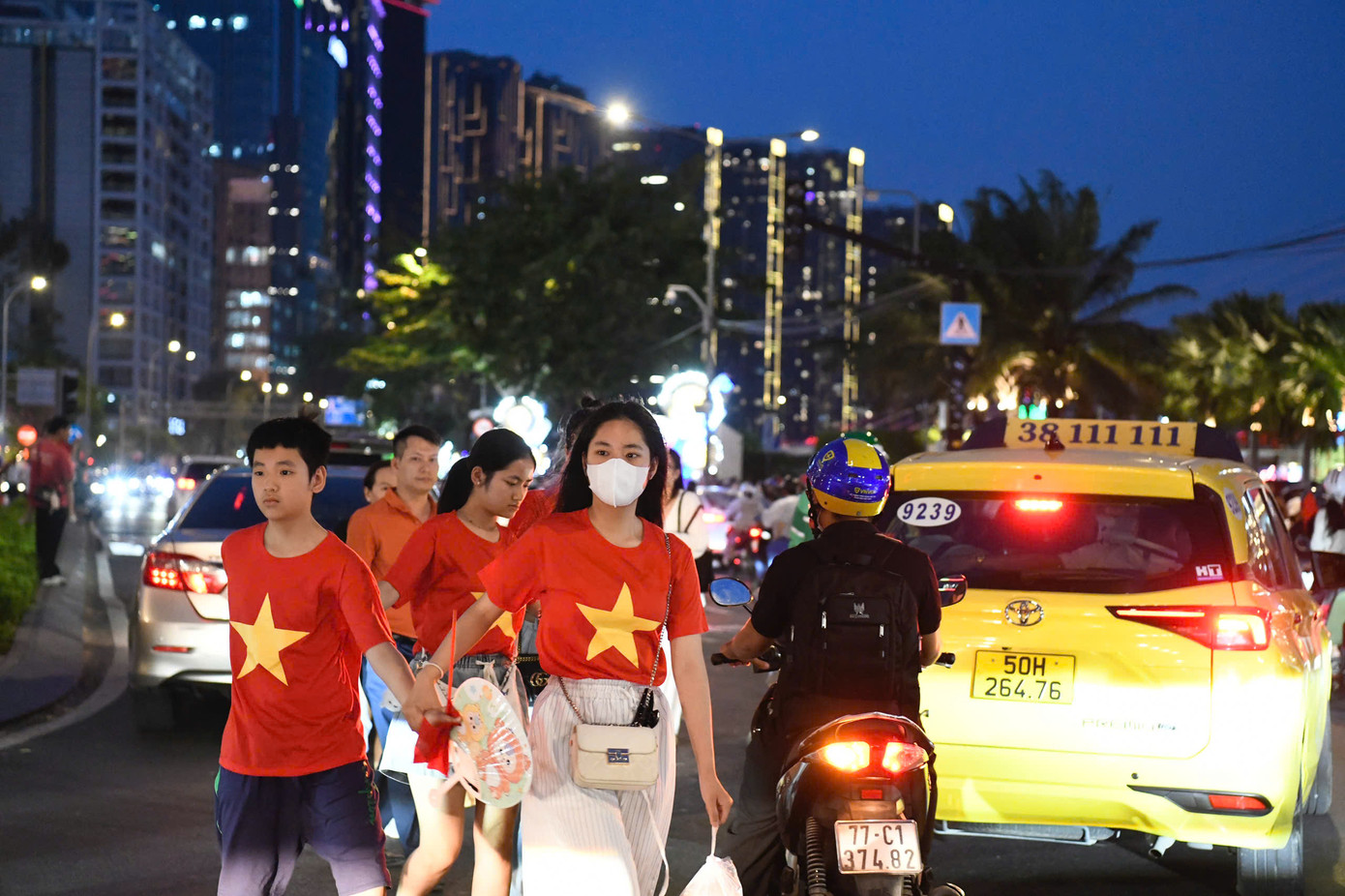 Nhiều gia đình mặc áo in hình cờ đỏ sao vàng, tay cầm cờ Tổ quốc đi bộ về hướng bến Bạch Đằng, dọc sông Bạch Đằng. Người dân háo hức trước sự kiện trọng đại của cả nước.