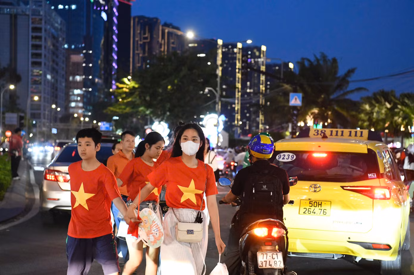 Nhiều gia đình mặc áo in hình cờ đỏ sao vàng, tay cầm cờ Tổ quốc đi bộ về hướng bến Bạch Đằng, dọc sông Bạch Đằng. Người dân háo hức trước sự kiện trọng đại của cả nước.