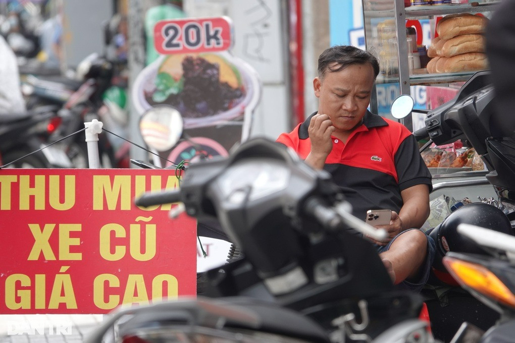 Nhiều chủ tiệm xe máy cũ ngáp dài, ngồi bấm điện thoại khi không có khách đến hỏi mua (Ảnh: Nguyễn Vy).