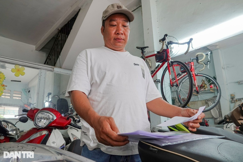 Cầm bộ hồ sơ mua bán trên tay, anh Hiếu rầu rĩ vì khách mua xe đã thanh toán nhưng thủ tục pháp lý chưa xong (Ảnh: Nguyễn Vy).