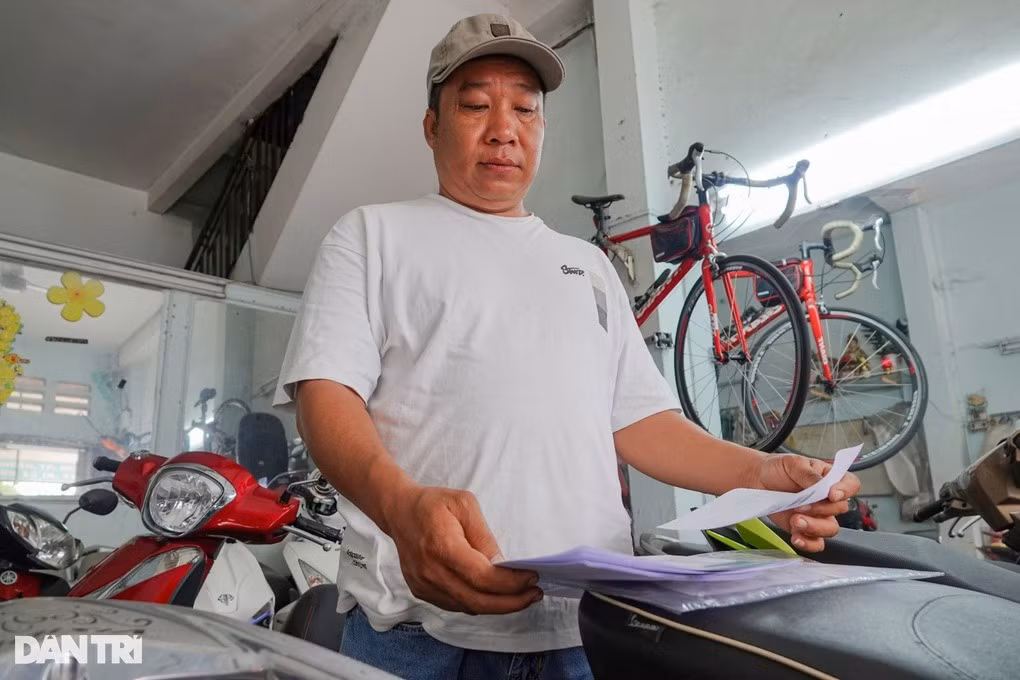 Cầm bộ hồ sơ mua bán trên tay, anh Hiếu rầu rĩ vì khách mua xe đã thanh toán nhưng thủ tục pháp lý chưa xong (Ảnh: Nguyễn Vy).
