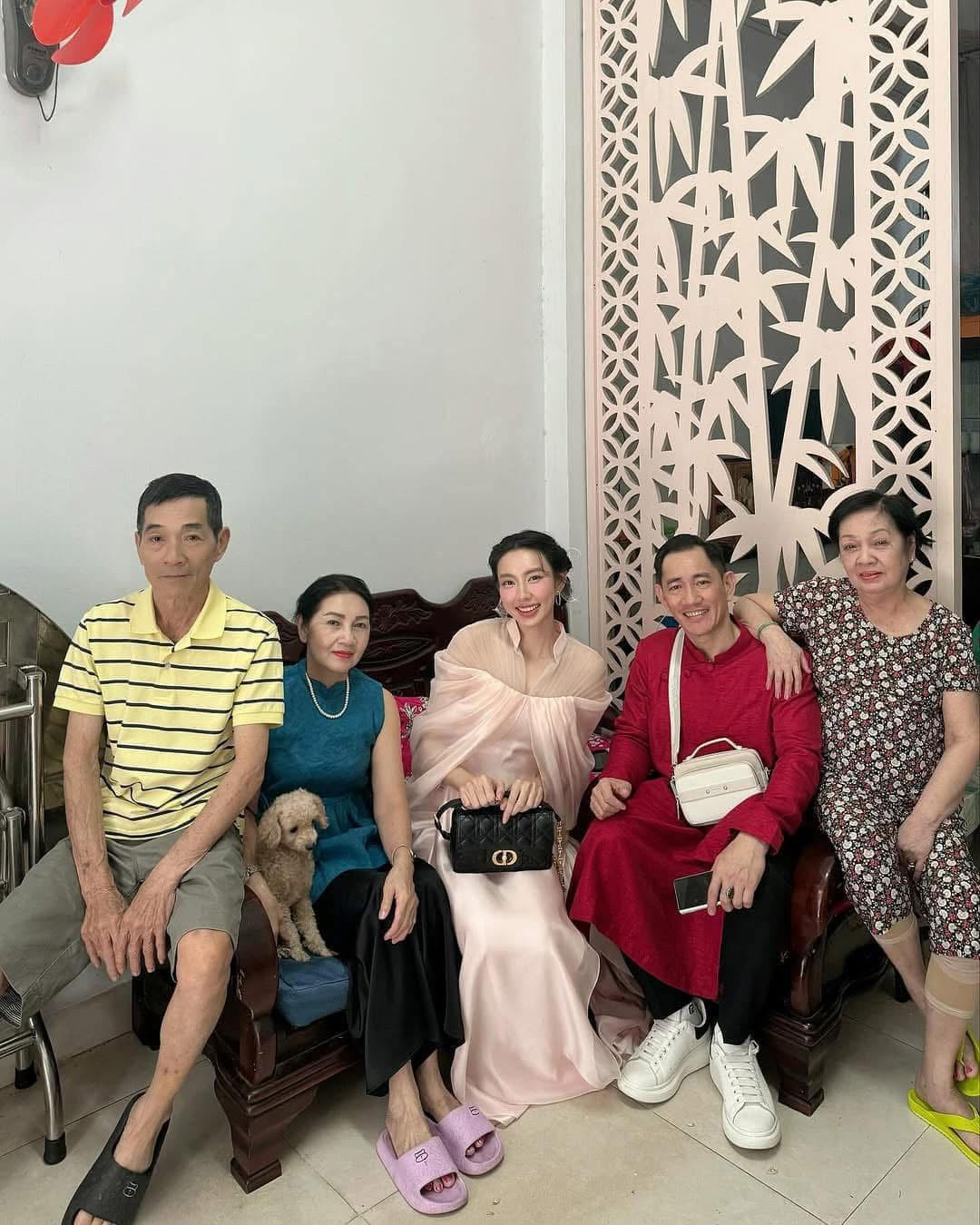 Hoa hậu Thùy Tiên khoe ảnh ăn Tết cùng gia đình. Hoa hậu Hòa bình Quốc tế 2021 trang điểm nhẹ nhàng, trang phục tông màu tươi sáng bên cha (áo dài đỏ) và người thân vào Mùng 1.