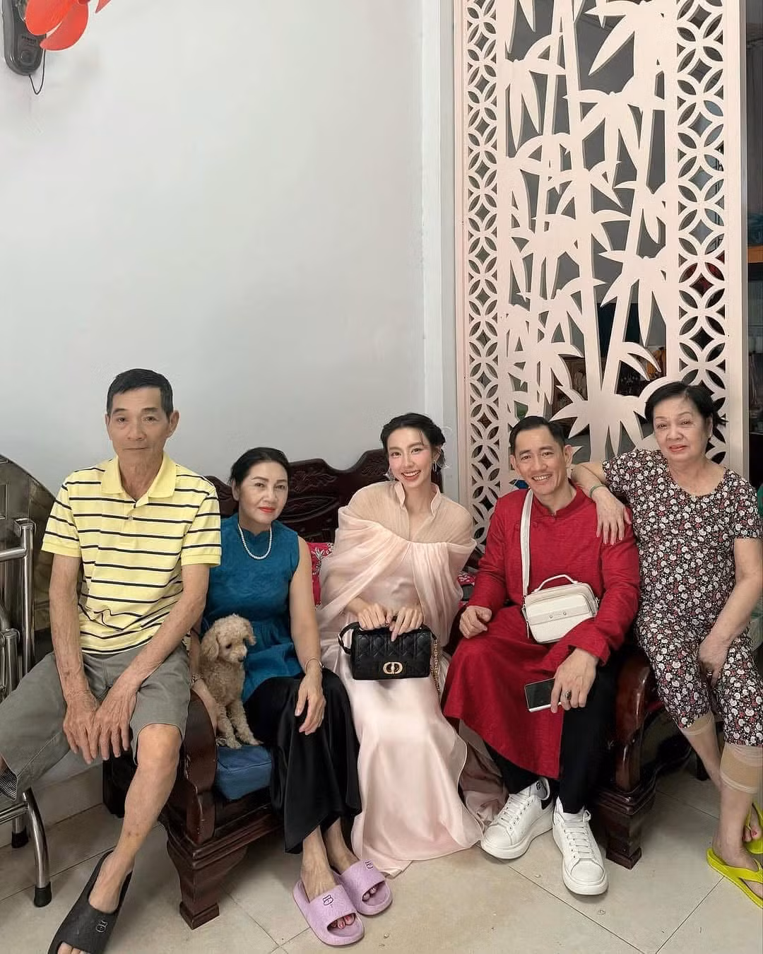 Hoa hậu Thùy Tiên khoe ảnh ăn Tết cùng gia đình. Hoa hậu Hòa bình Quốc tế 2021 trang điểm nhẹ nhàng, trang phục tông màu tươi sáng bên cha (áo dài đỏ) và người thân vào Mùng 1.