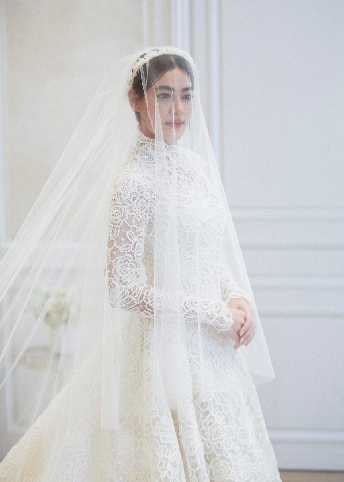 Cô dâu tinh khôi trong áo cưới dạ hội kín đáo và sang trọng thuộc thương hiệu thời trang cao cấp. Phần tà che đầu phủ kín mặt, kéo dài đến chân tôn lên vẻ thướt tha cho sao nữ nổi tiếng người Thái.