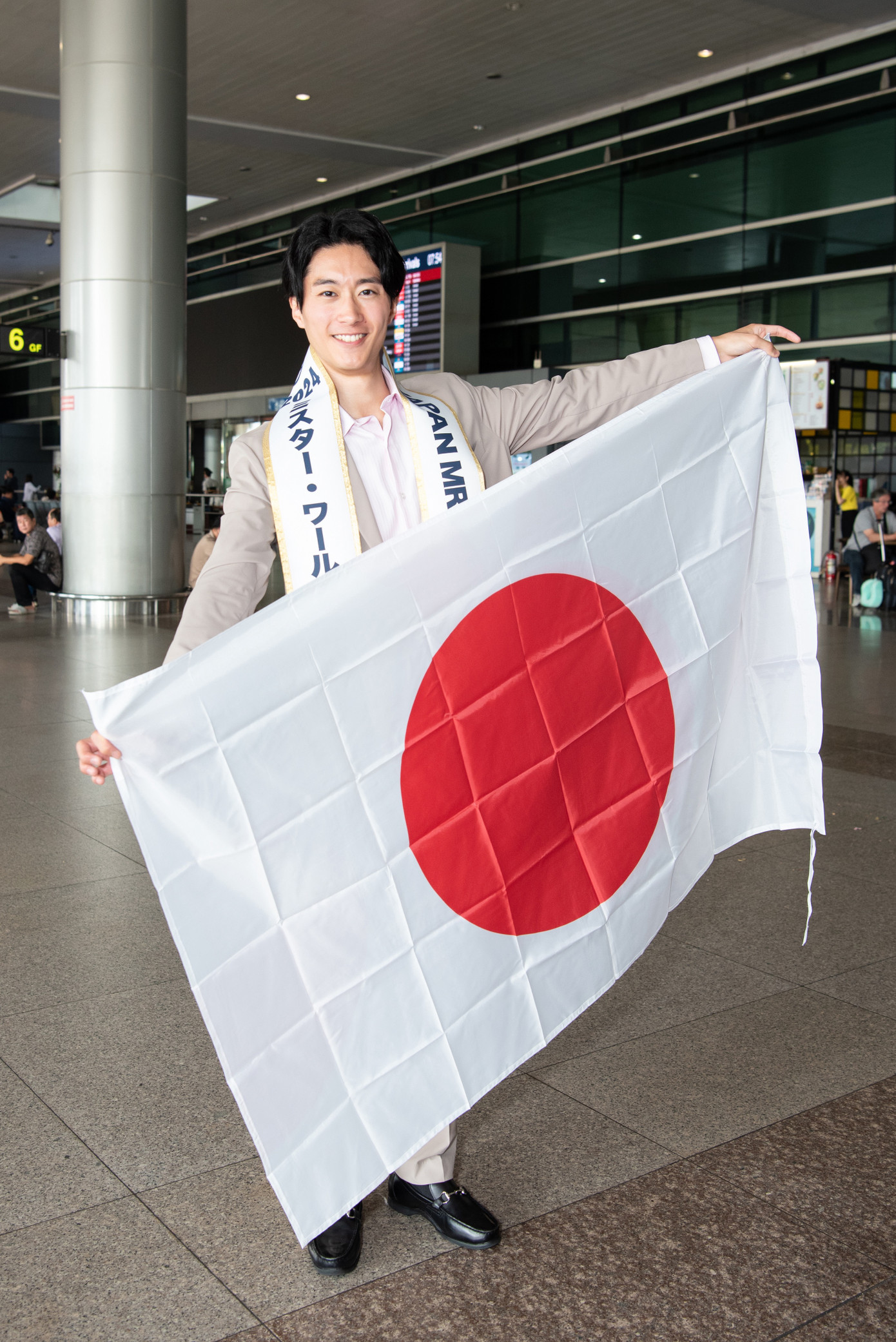 Mr World Japan đáp chuyến bay sớm đến Việt Nam sáng 5/11. Đại diện đến từ Nhật Bản chụp ảnh với quốc kỳ tại sân bay trước khi nhập cuộc Nam vương Thế giới.