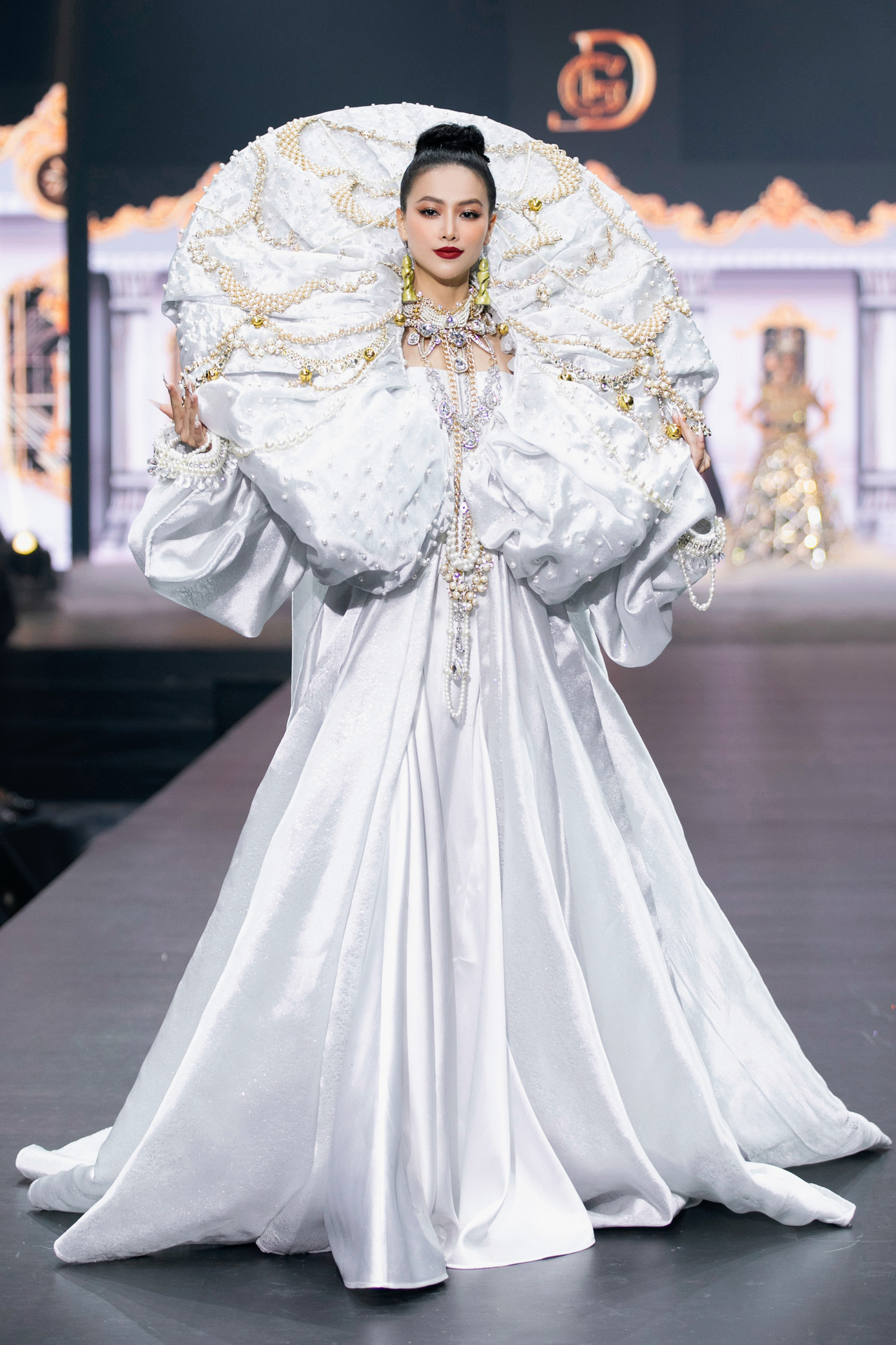 Phương Khánh trong bộ trang phục trắng, phần vai áo được đính hoa văn, ngọc trai cầu kỳ. Theo nhà thiết kế, đây là cuộc chơi của phom dáng, được may đo, thực hiện thủ công hoàn toàn.