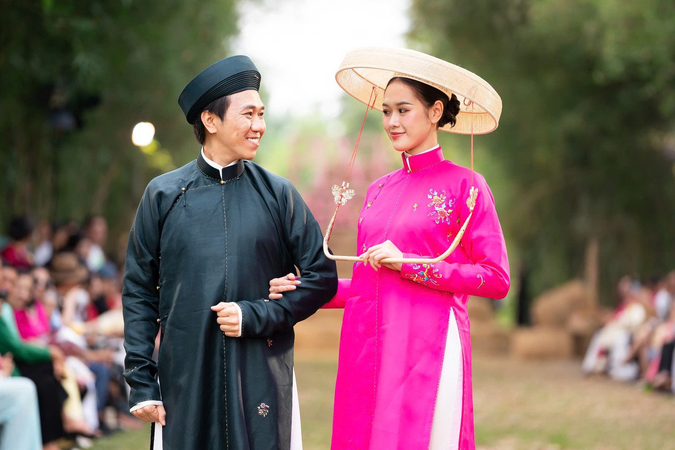 Vợ chồng Anh Đức - Anh Phạm diện áo dài ngũ thân lấy cảm hứng từ trang phục cưới của người dân Nam bộ xưa. Áo có dáng tay và phom người rộng, đi kèm là trang phục nón cụ quai cung cách điệu, phụ kiện thường thấy của phụ nữ xưa.