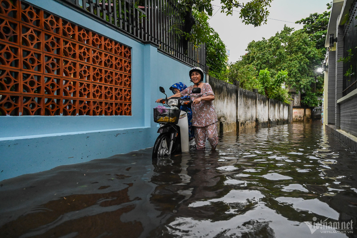 Sau khoảng 1 tiếng, mưa tạnh nhưng nước rút chậm, con hẻm nhỏ trên đường Đặng Thị Ràng nước vẫn ngập tới đầu gối. Bà Lan dắt xe đưa cháu về nhà phải đi chậm để tránh vấp ngã.