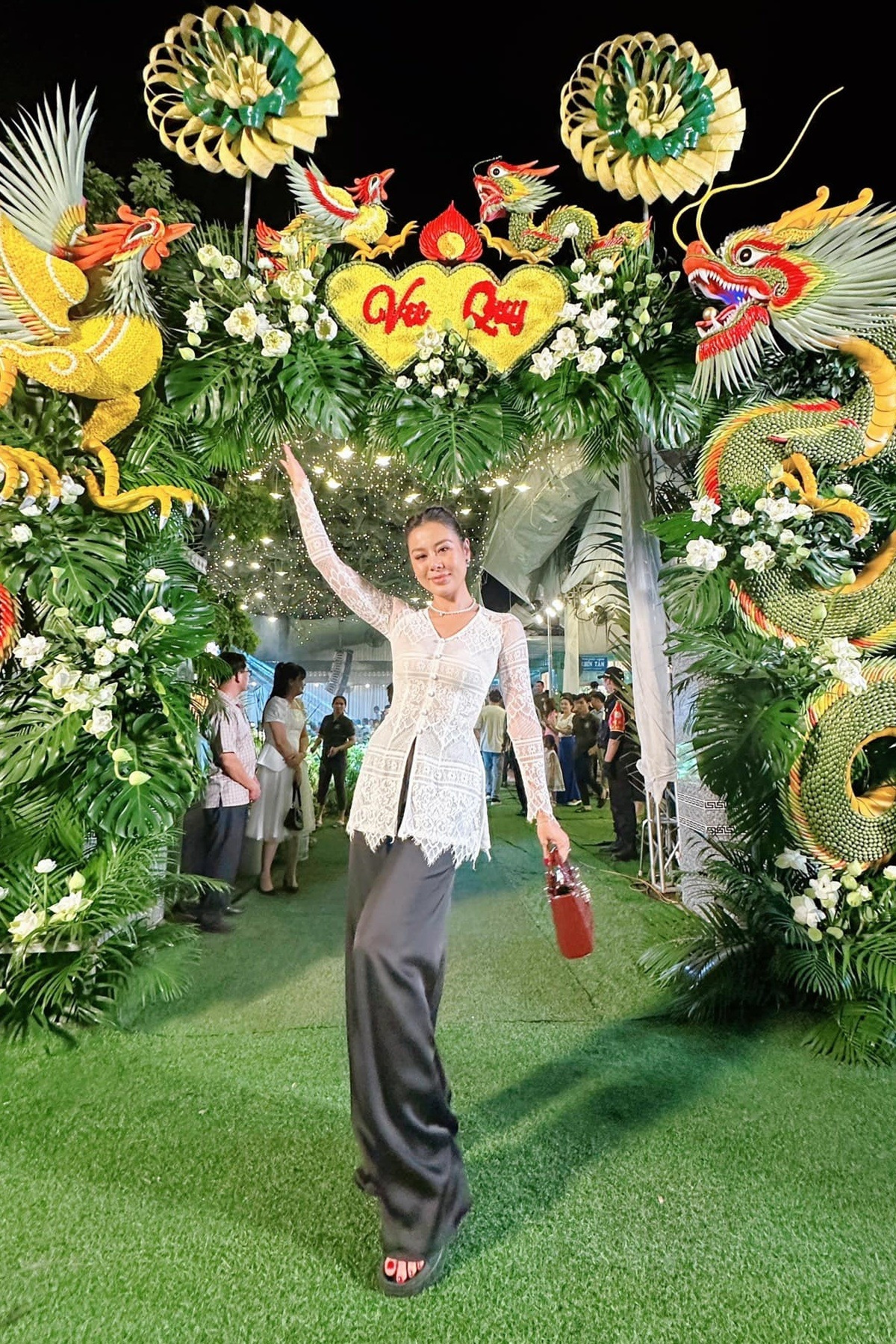 Nam Thư cũng diện đồ bà ba cách tân dự tiệc cưới đồng nghiệp. Trước đó cô check-in trước cổng hoa được trang trí bằng lá dừa, cau và hoa tươi.