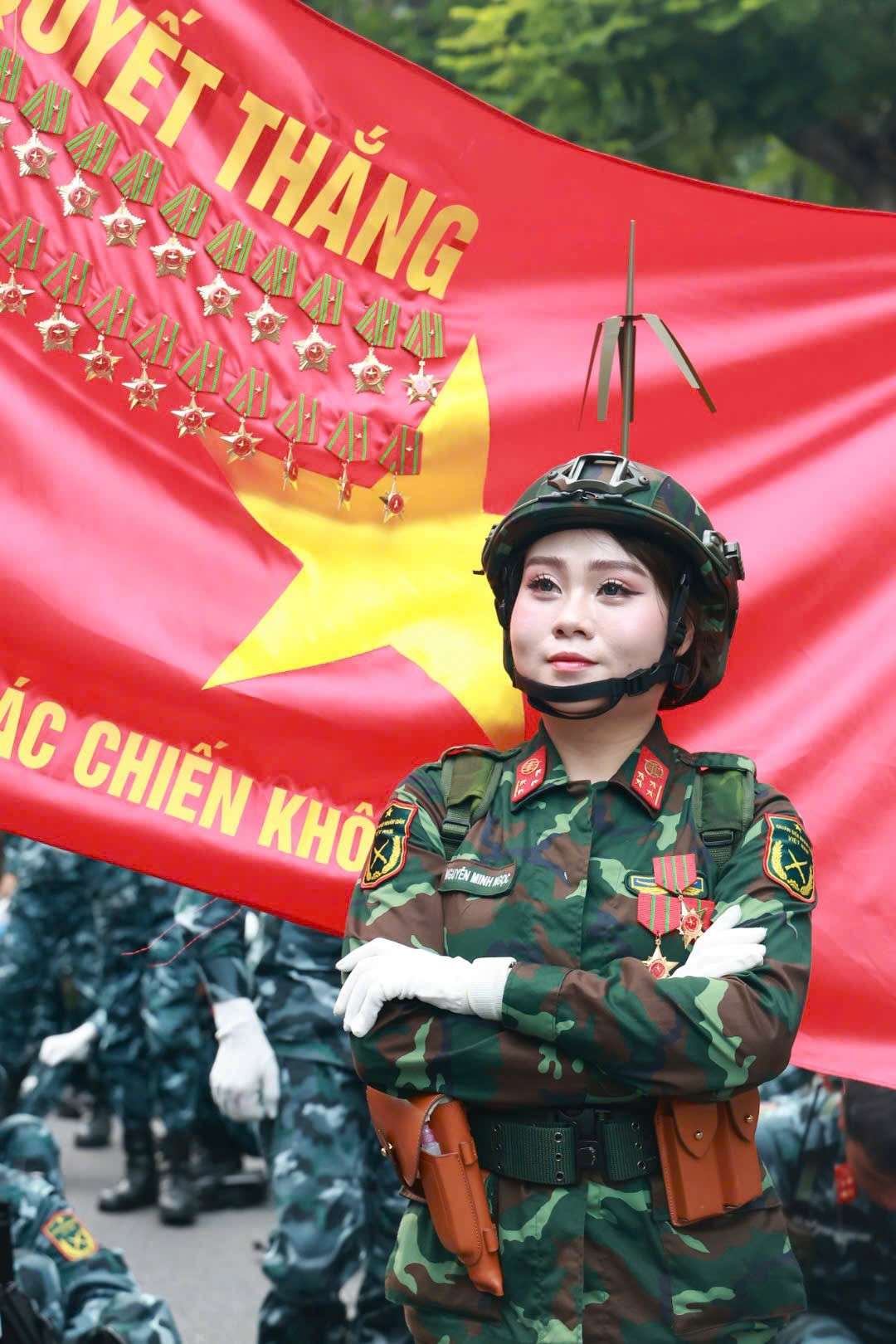 Khoảnh khắc nữ quân nhân thuộc Khối nữ gìn giữ hòa bình Liên Hợp Quốc (trái) và quân nhân thuộc Khối nữ sĩ quan Thông tin trước lá cờ Quyết thắng, thể hiện sự tự hào khi nằm trong đội ngũ lực lượng Quân đội Nhân dân Việt Nam.