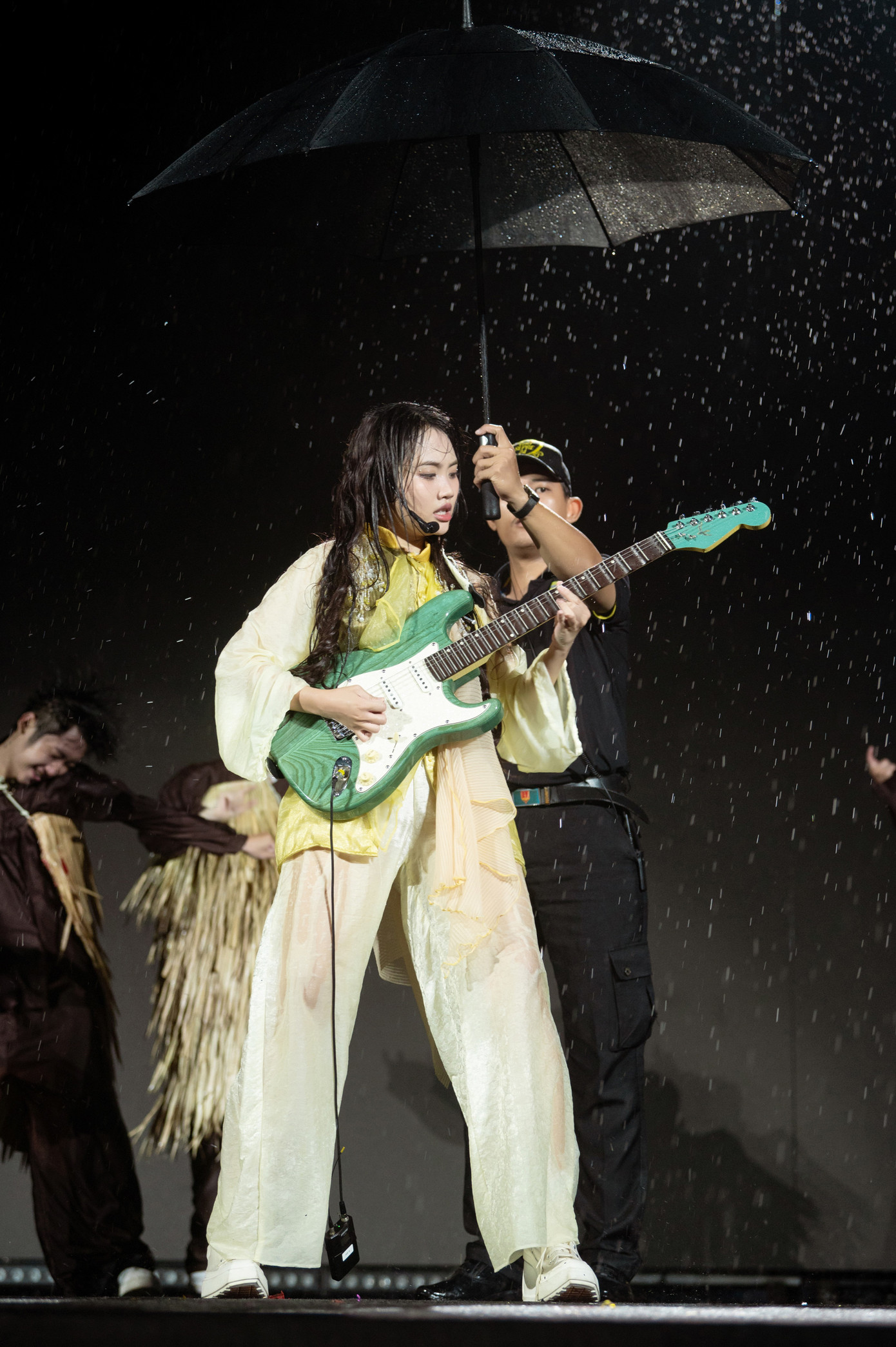 Hình ảnh Phương Mỹ Chi đội mưa, chơi guitar thể hiện Rock hạt gạo sau ba tiếng biểu diễn.