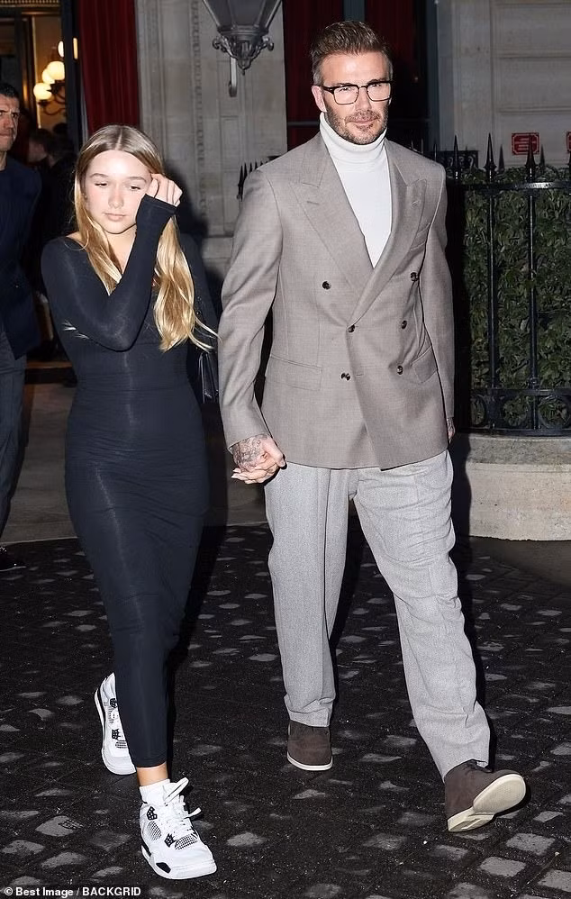 Beckham phối vest xám cùng áo len cổ lọ. Beckham được khen giữ được phong độ ở tuổi 49. Cựu danh thủ người Anh nắm tay con gái dự show thời trang.