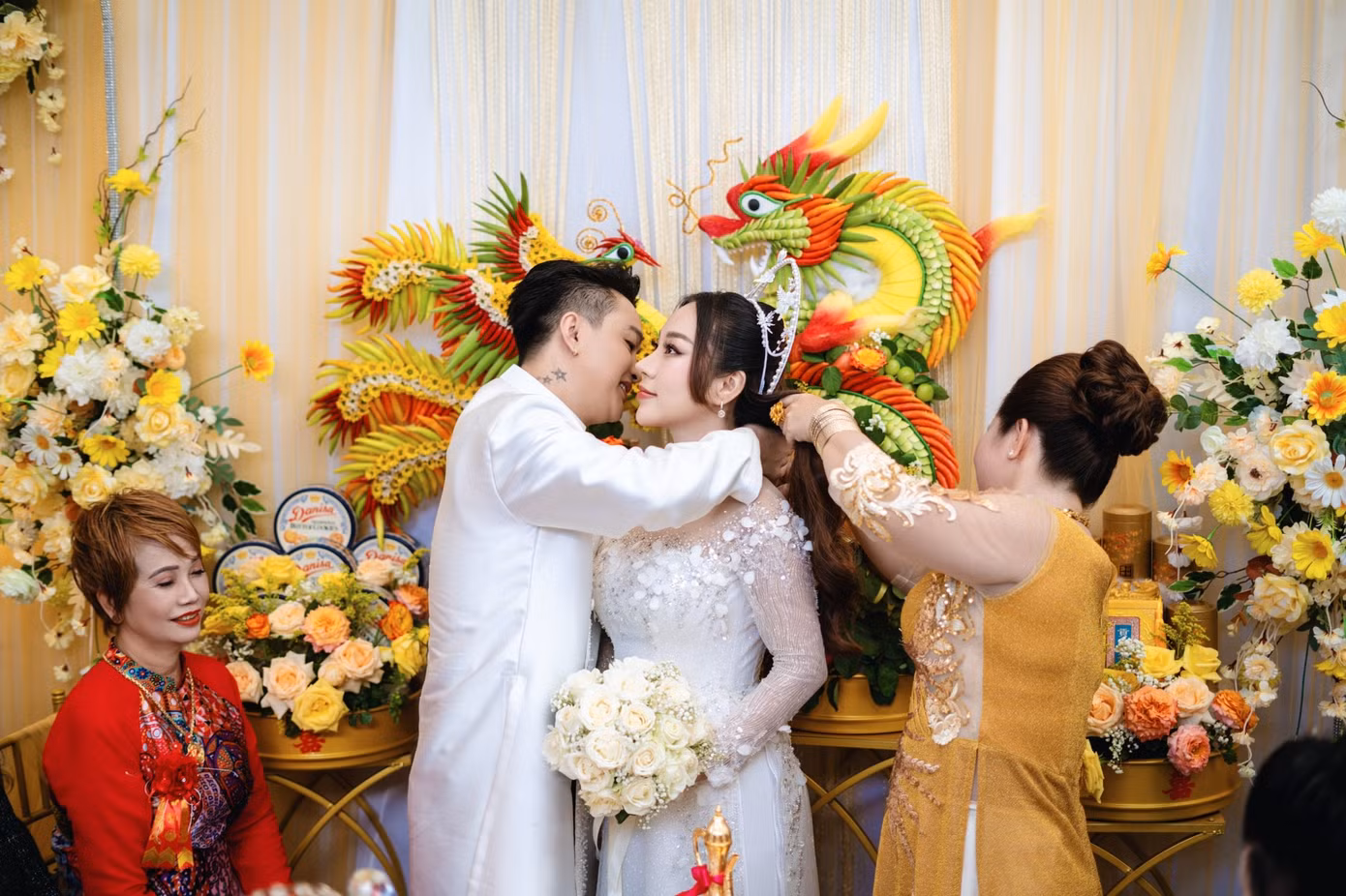 Hình ảnh chú rể TiTi trao quà cho cô dâu trong lễ hỏi. Không gian tiệc trang trí bằng hoa tươi, nổi bật với lễ vật khắc hình rồng phượng. Hình ảnh chú rể TiTi trao quà cho cô dâu trong lễ hỏi. Không gian tiệc trang trí bằng hoa tươi, nổi bật với lễ vật khắc hình rồng phượng.