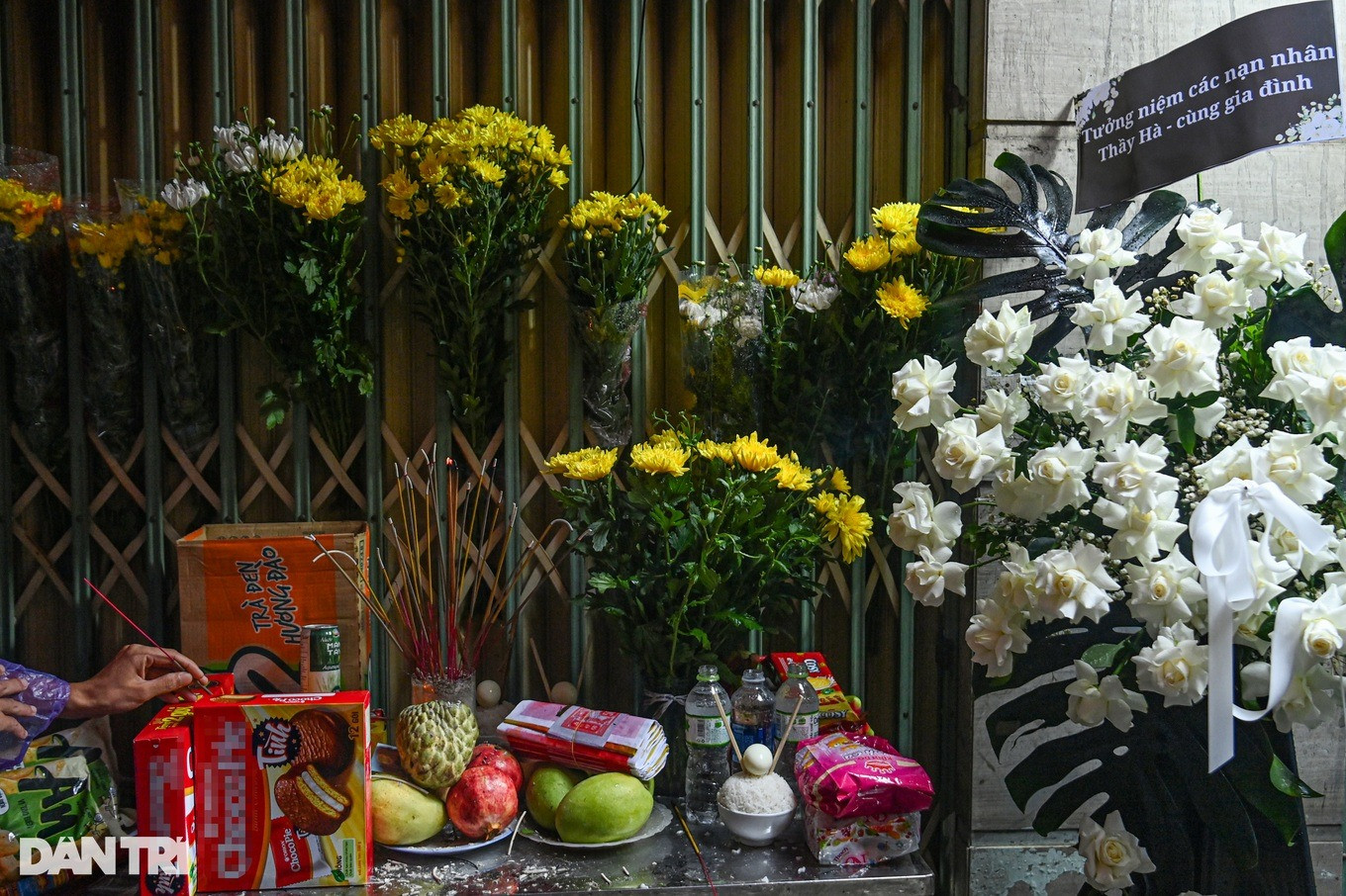 Người dân cài hoa, thắp hương tưởng niệm trước cửa chung cư mini (Ảnh: Mạnh Quân).