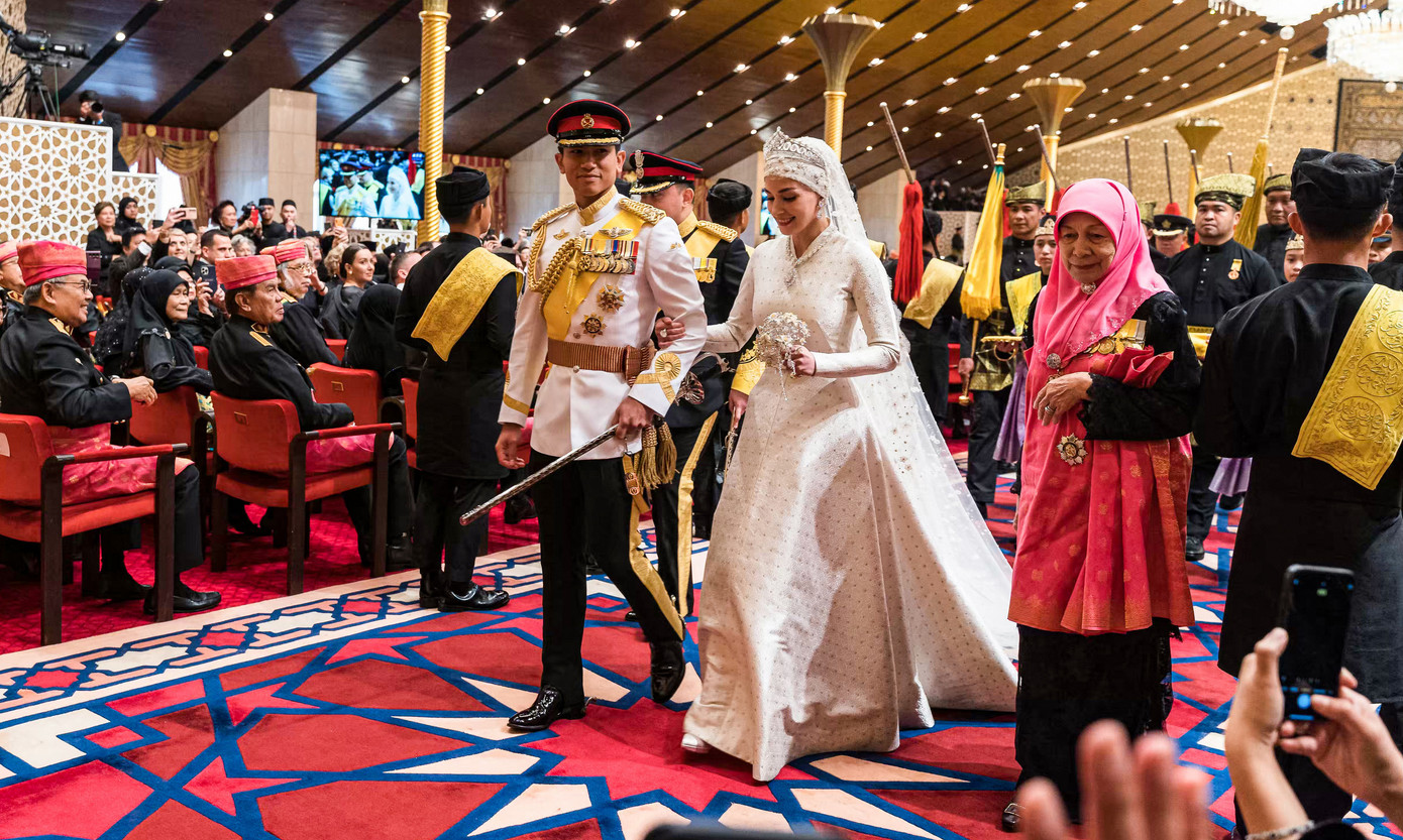 Theo AFP, Istiadat Bersanding Pengantin Diraja là sự kiện nổi bật nhất trong lễ cưới. Cô dâu đầu quấn khăn, đội vương miện và trang phục in hoa văn truyền thống. Hoàng tử mặc quân phục, vai mang huy chương.
