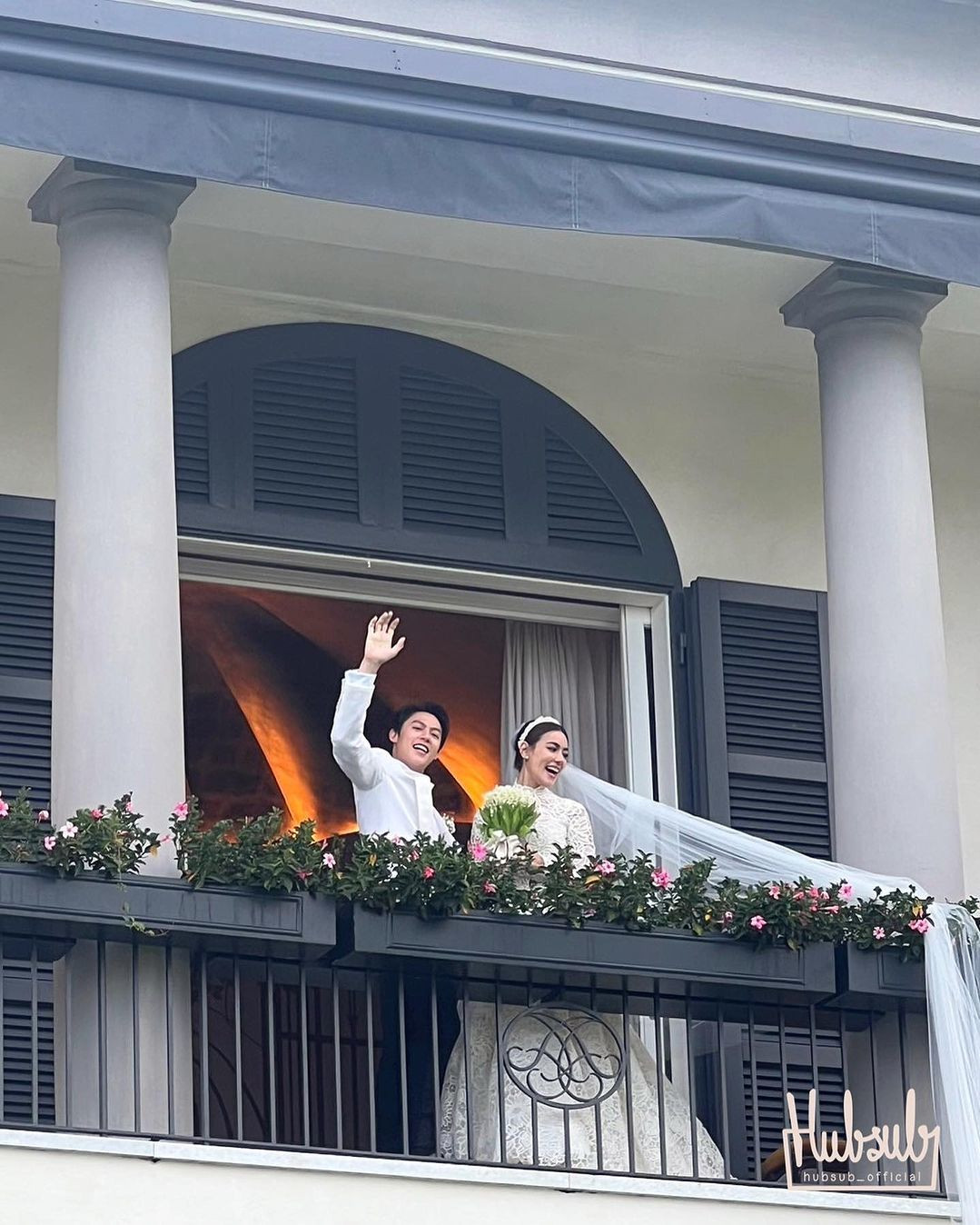Cặp sao đẹp đôi nhất Thái Lan bên trên biệt thự nhìn xuống quan khách. Khung cảnh lãng mạn được ví như đám cưới cổ tích hoàng gia, nơi cô dâu - chú rể vẫy tay chào quan khách từ ban công biệt thự.