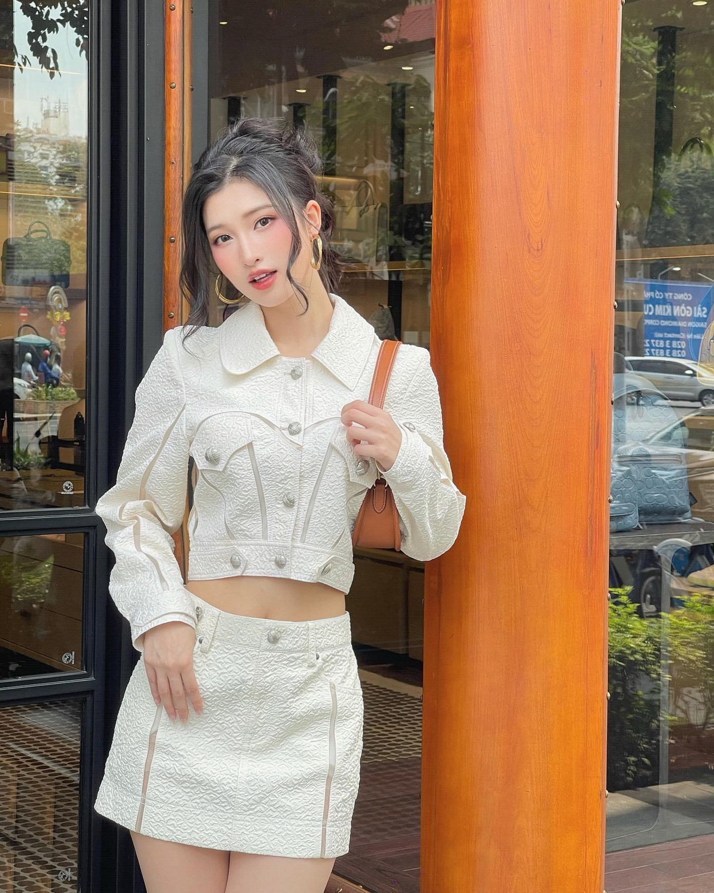 Thiết kế crop top và chân váy ngắn chữ A chất liệu tweed hoa văn chìm mang đến cảm giác thanh lịch. Kiểu tóc búi cao phối cùng khuyên tai lớn mang lại sự phá cách cho Phương Nhi.