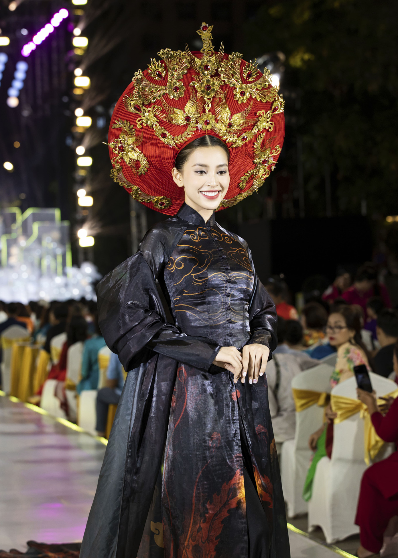 Trong sự kiện Lễ hội Áo dài TPHCM 2024, Hoa hậu Tiểu Vy gây chú ý với gương mặt tươi trẻ. Thiết kế với điểm nhấn phần mấn đội đầu chạm trổ tinh xảo làm tôn lên nét đẹp của Hoa hậu Việt Nam 2018.