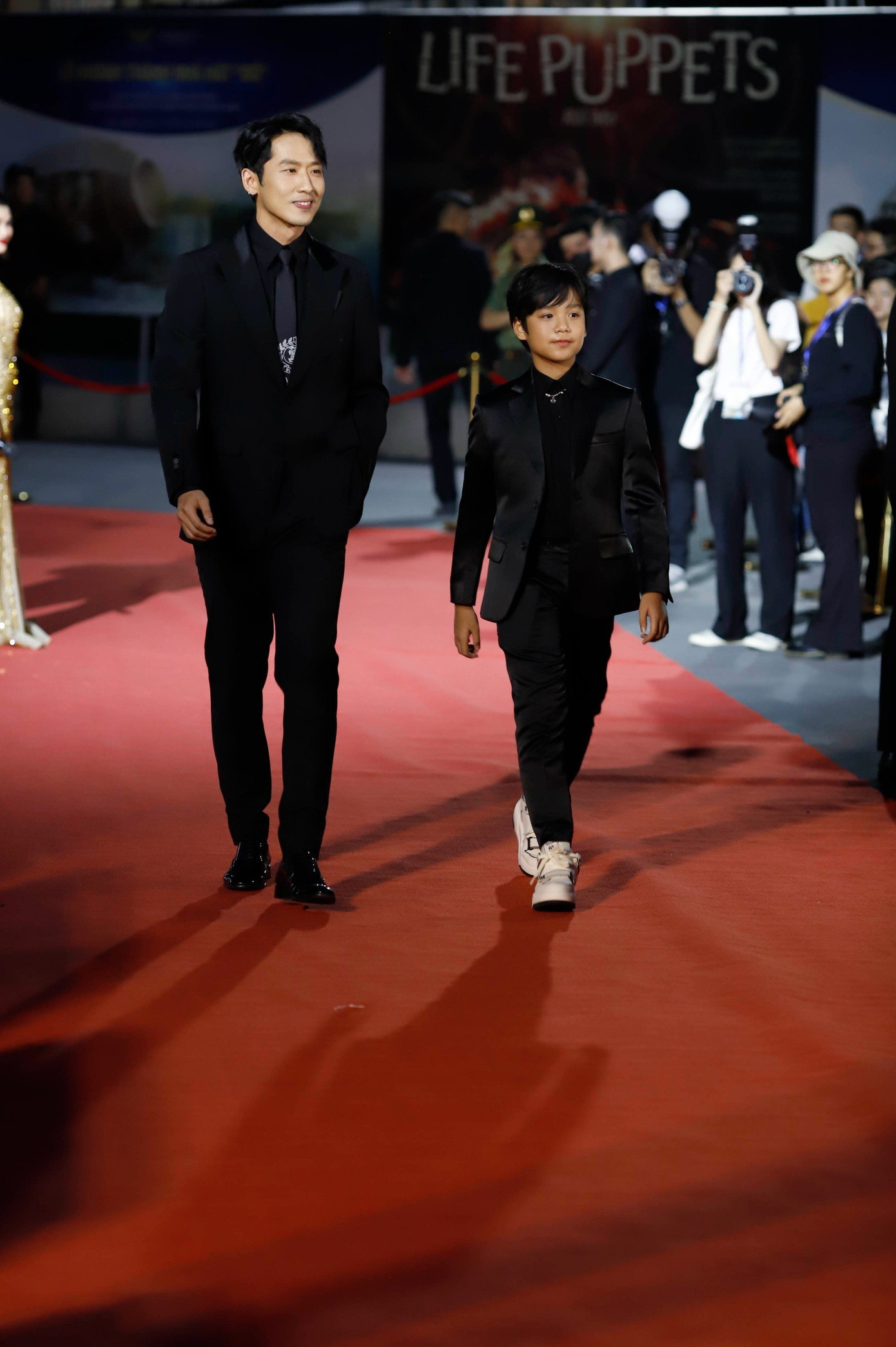 Diễn viên Tuấn Trần mặc vest đen bảnh bao sải bước tại sự kiện. Năm 2021, diễn viên trẻ giành giải Nam diễn viên chính xuất sắc - lĩnh vực Điện ảnh với vai diễn trong tác phẩm điện ảnh Bố già.