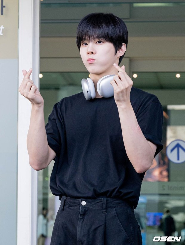 Kim Woo Seok thân thiện, tạo dáng trước ống kính phóng viên. Nam ca sĩ mặc đơn giản, diện nguyên cây đen trong chuyến bay đến Việt Nam.