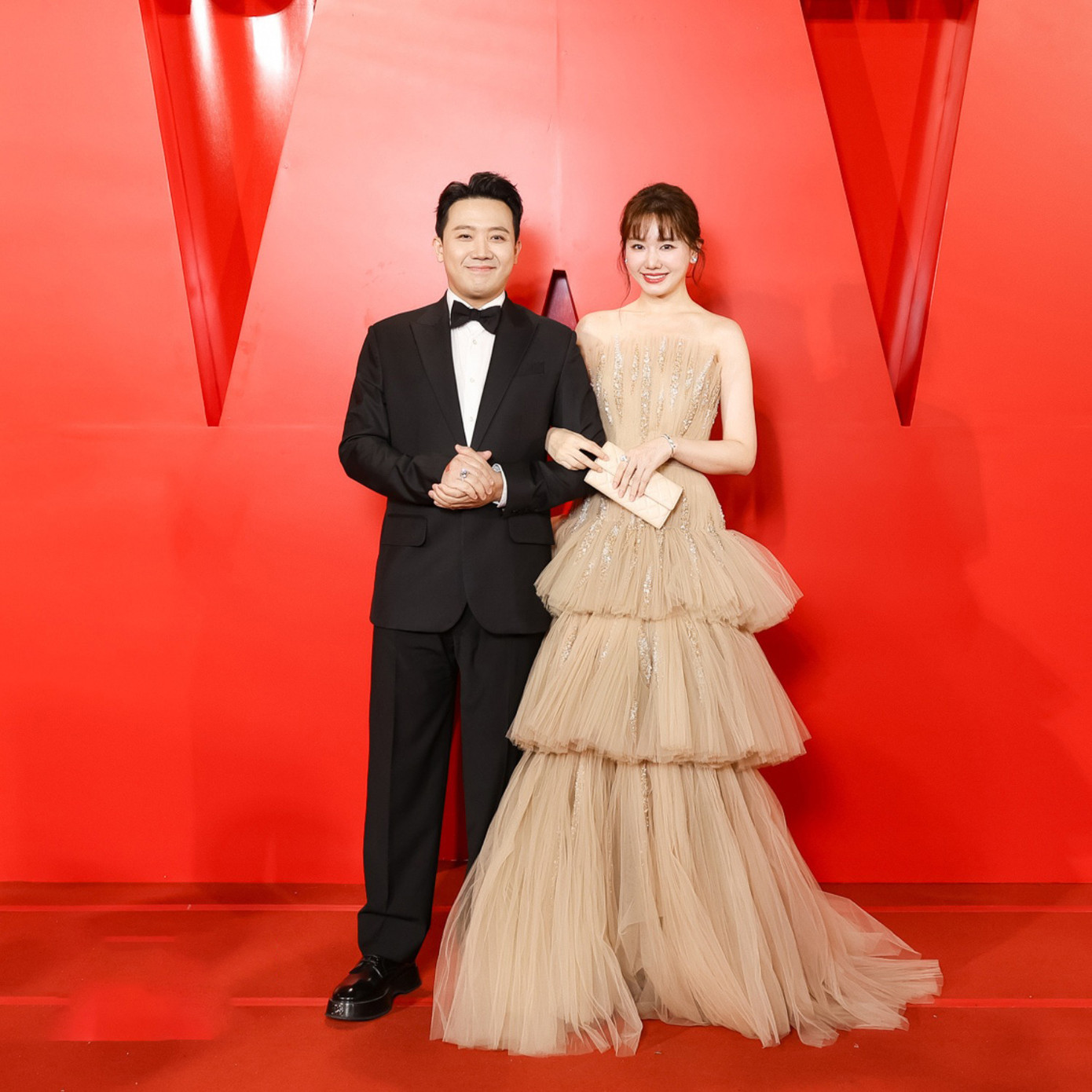 Trấn Thành mặc vest đen bảnh bao sự lễ trao giải cùng vợ. Hari Won diện thiết kế xếp tầng ấn tượng, tôn da.