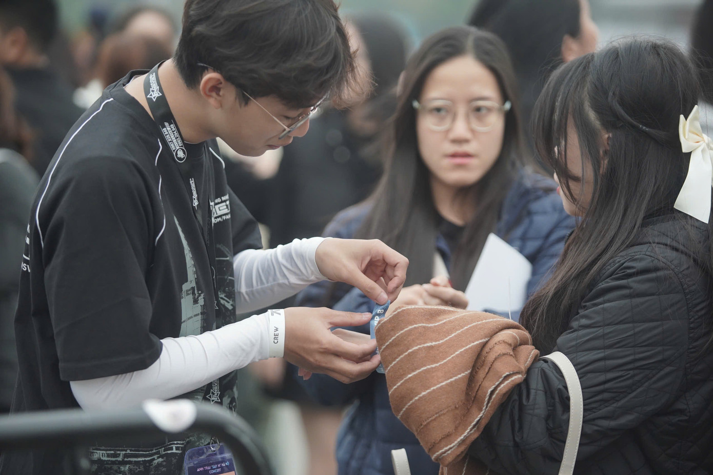 Thành viên ban tổ chức giúp khán giả đeo vòng tay sau khi đổi vé điện tử thành công.