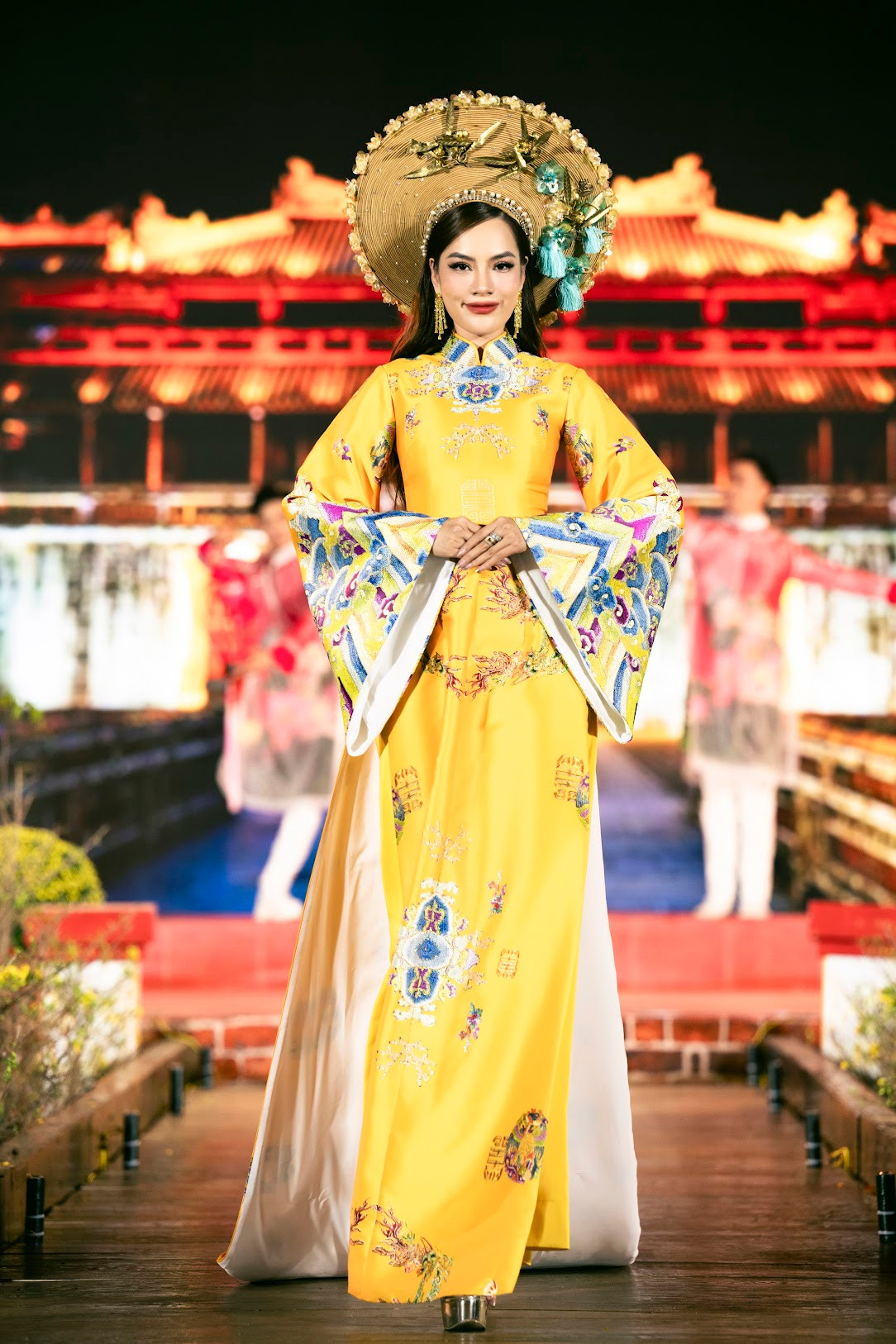 Hoa hậu Lê Hoàng Phương mở màn bộ sưu tập áo dài truyền thống với hoa văn đậm chất cung đình Huế. Phần mấn cách điệu, to bản làm nổi bật trang phục vàng cảm hứng hoàng tộc.